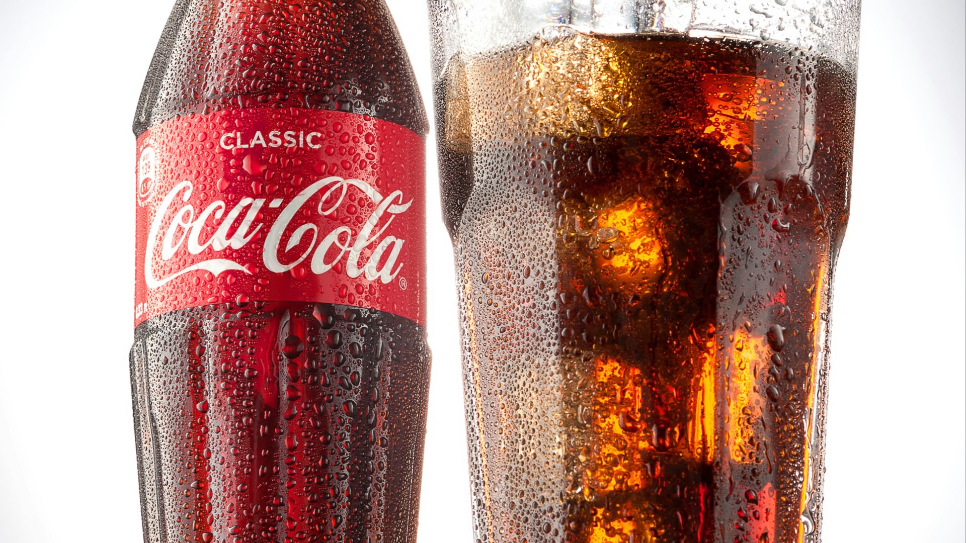 coca cola bottle beside drinking glass