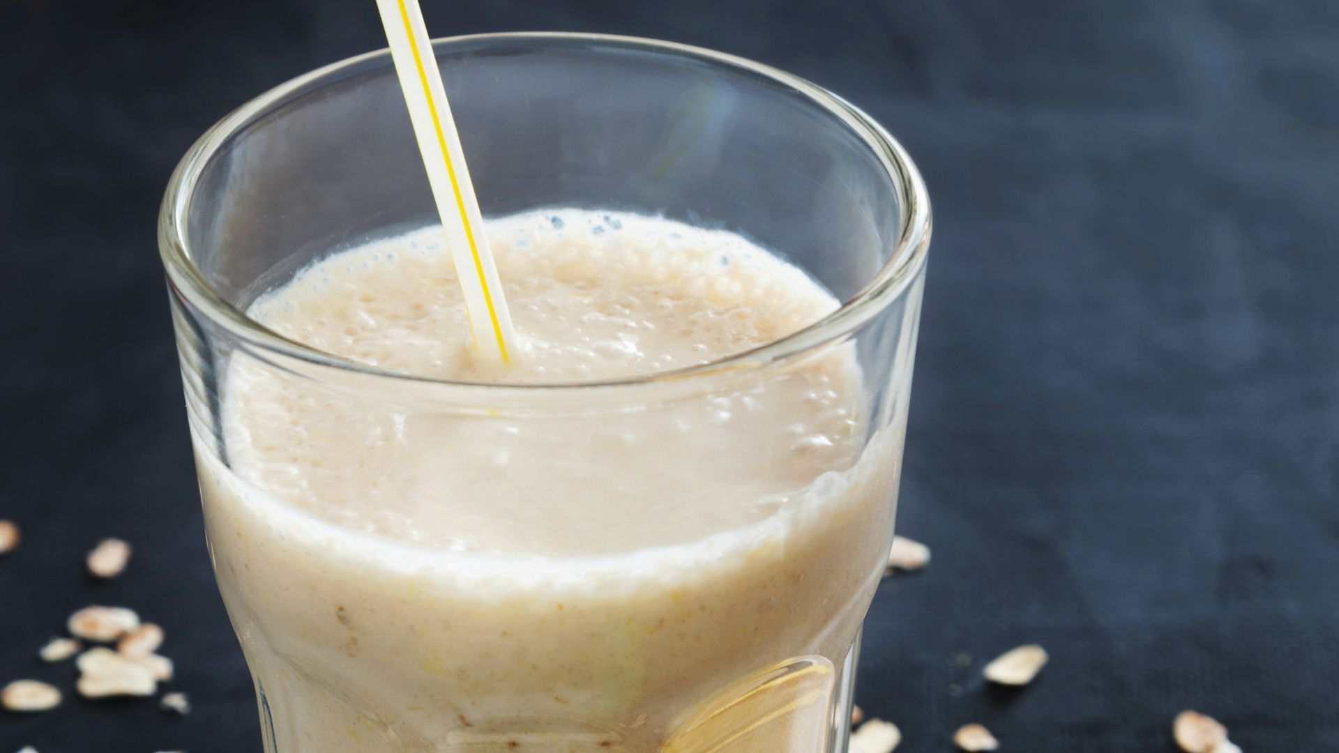 a banana smoothie in a glass next to a plate of sliced bananas