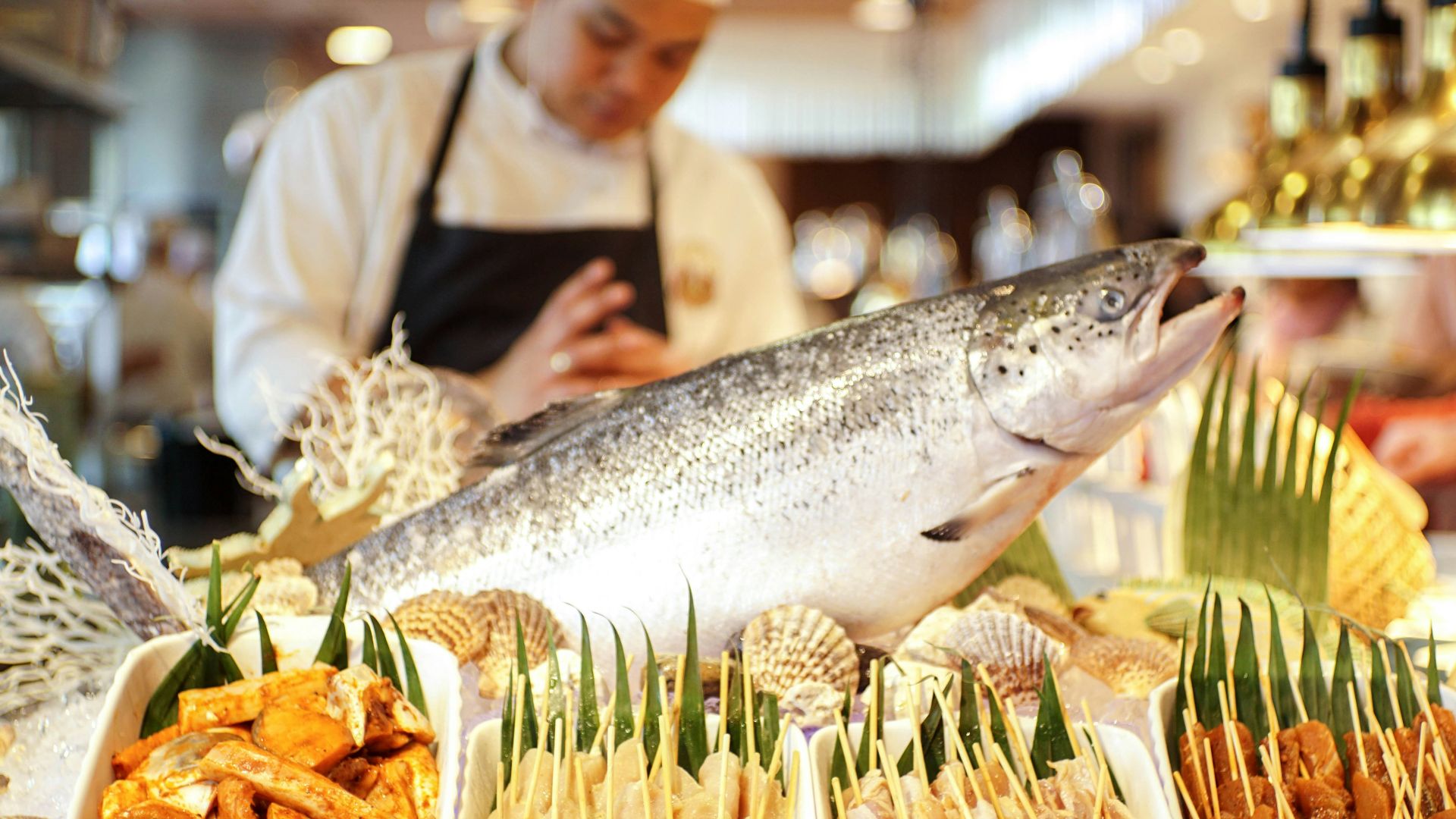 man in white apron holding fish