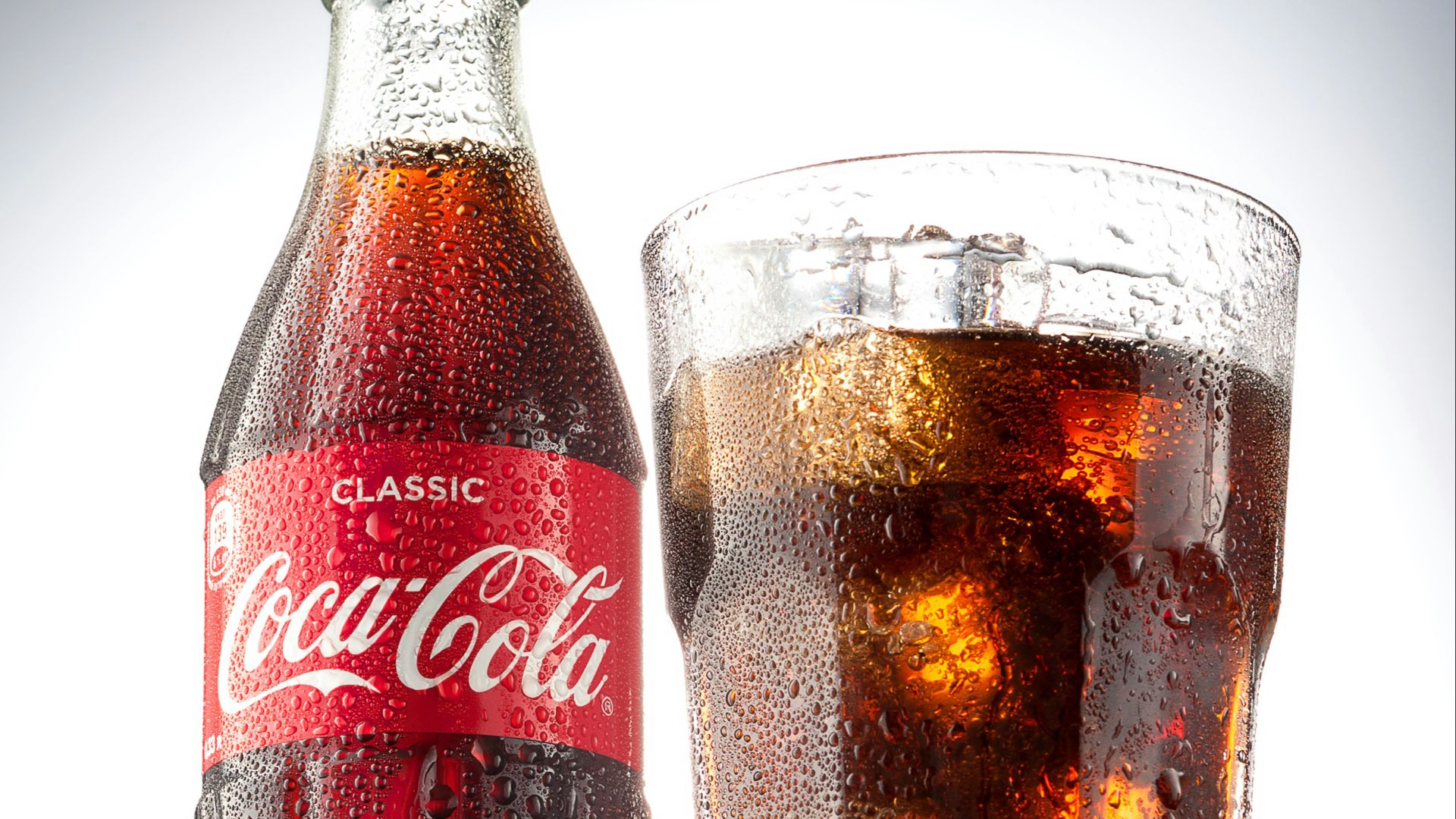 coca cola bottle beside drinking glass