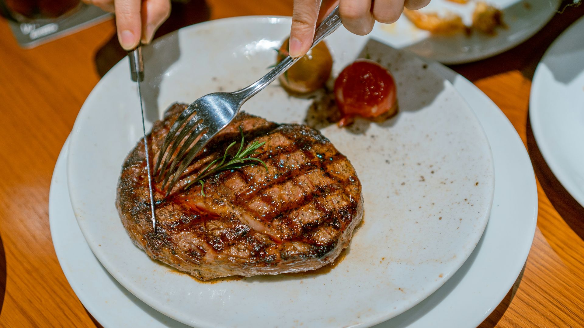 a person cutting into a steak on a plate