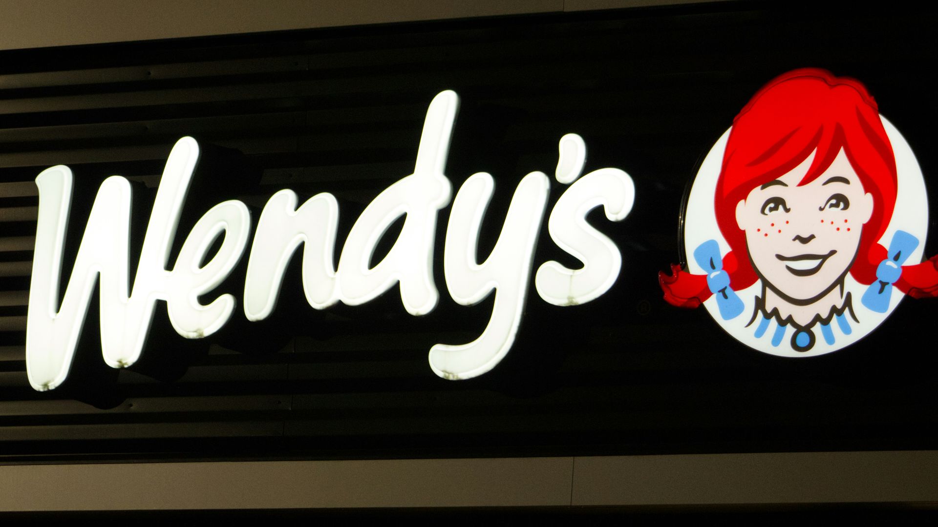 A wendy's sign is lit up at night