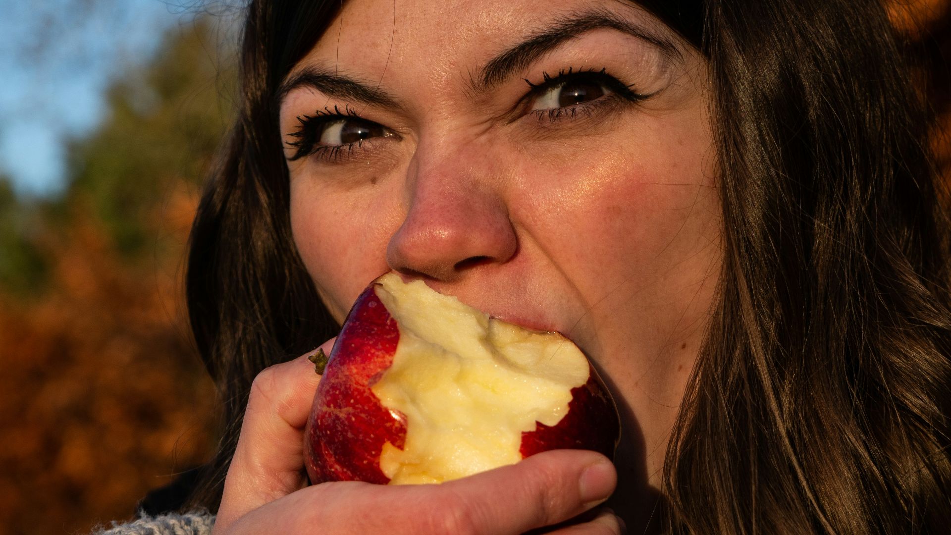 woman in gray sweater holding sliced of apple
