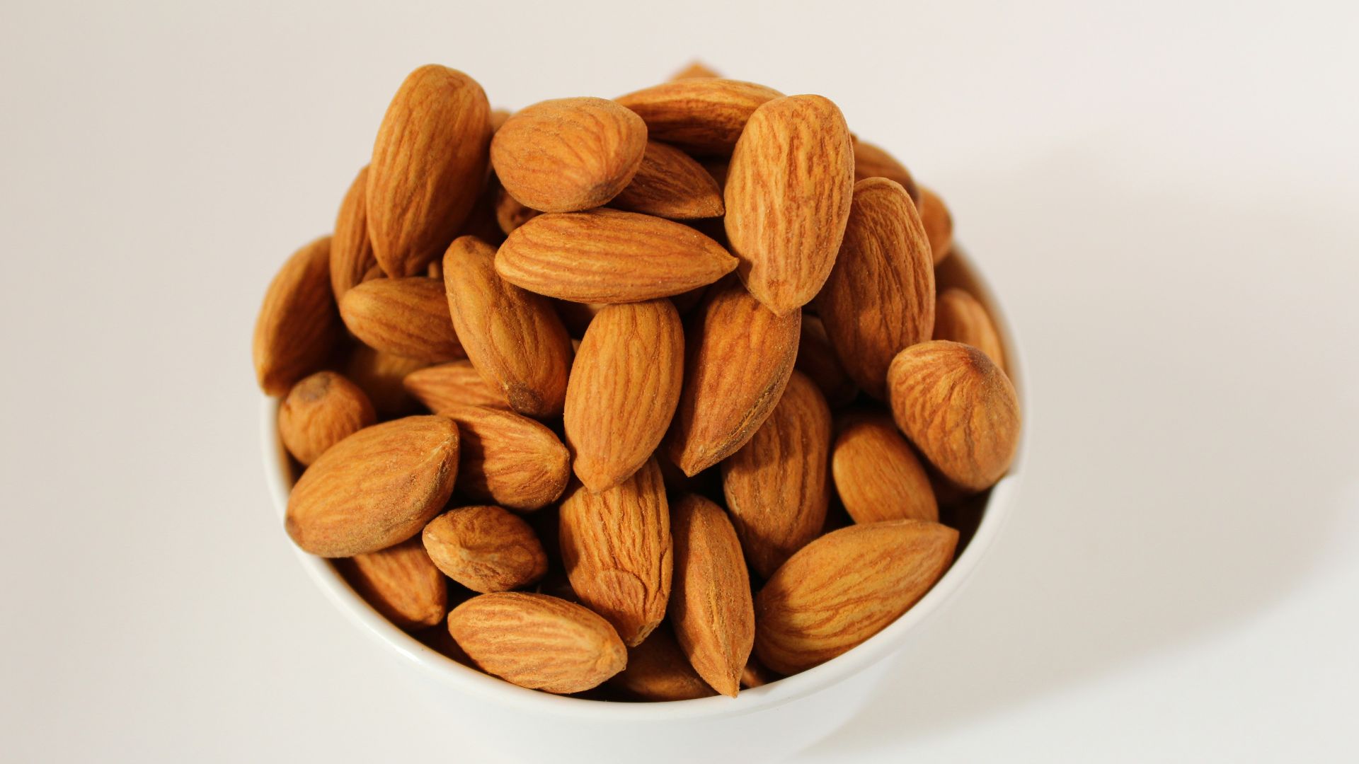 brown almond nuts on white ceramic bowl