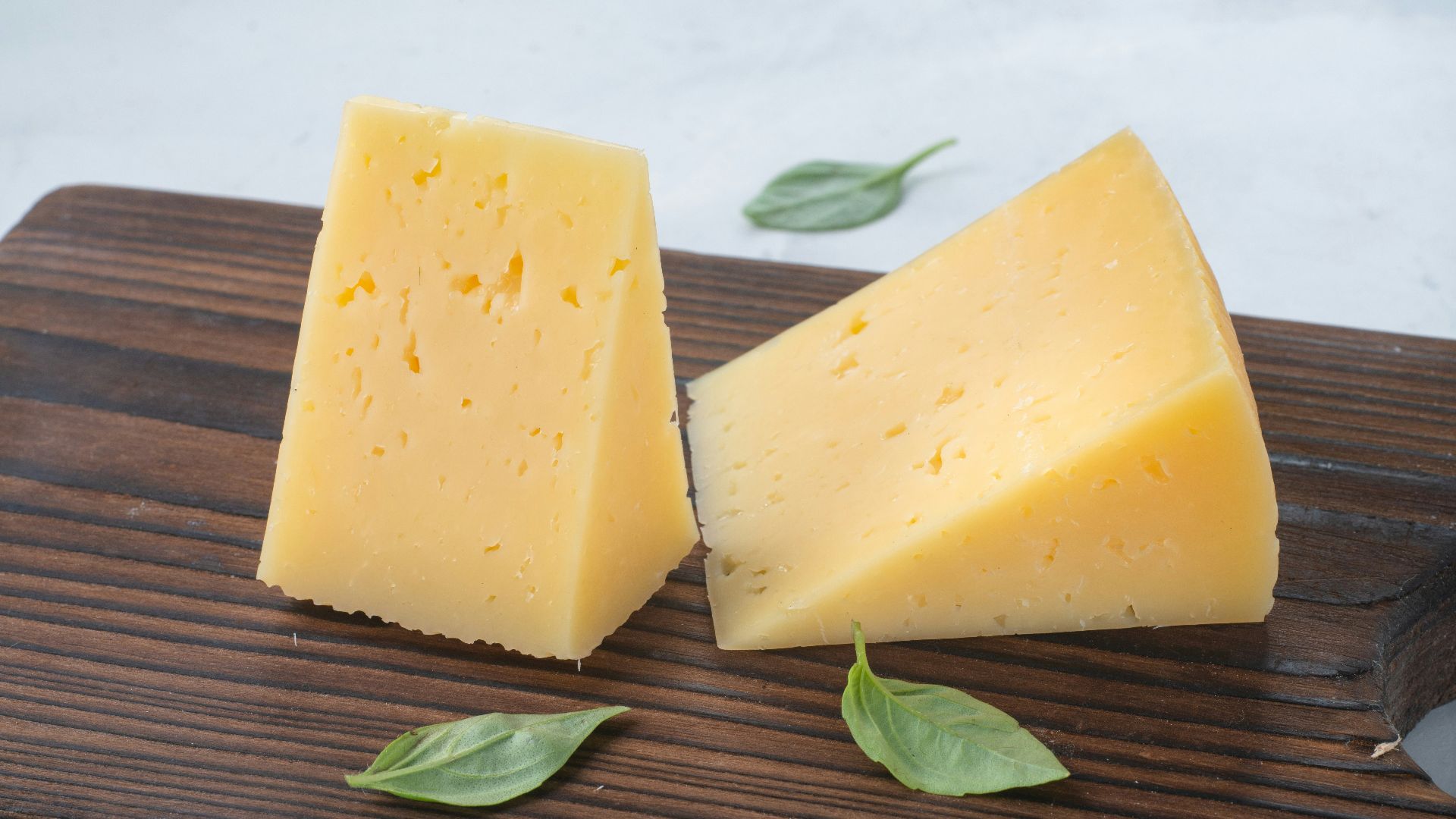 a couple of pieces of cheese sitting on top of a wooden cutting board