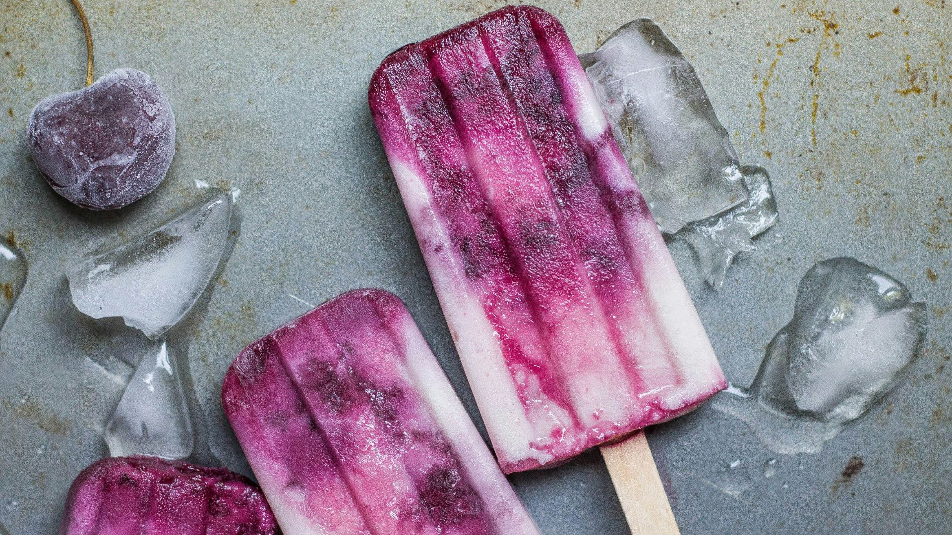 purple and white ice pop lying on wet ground with ice