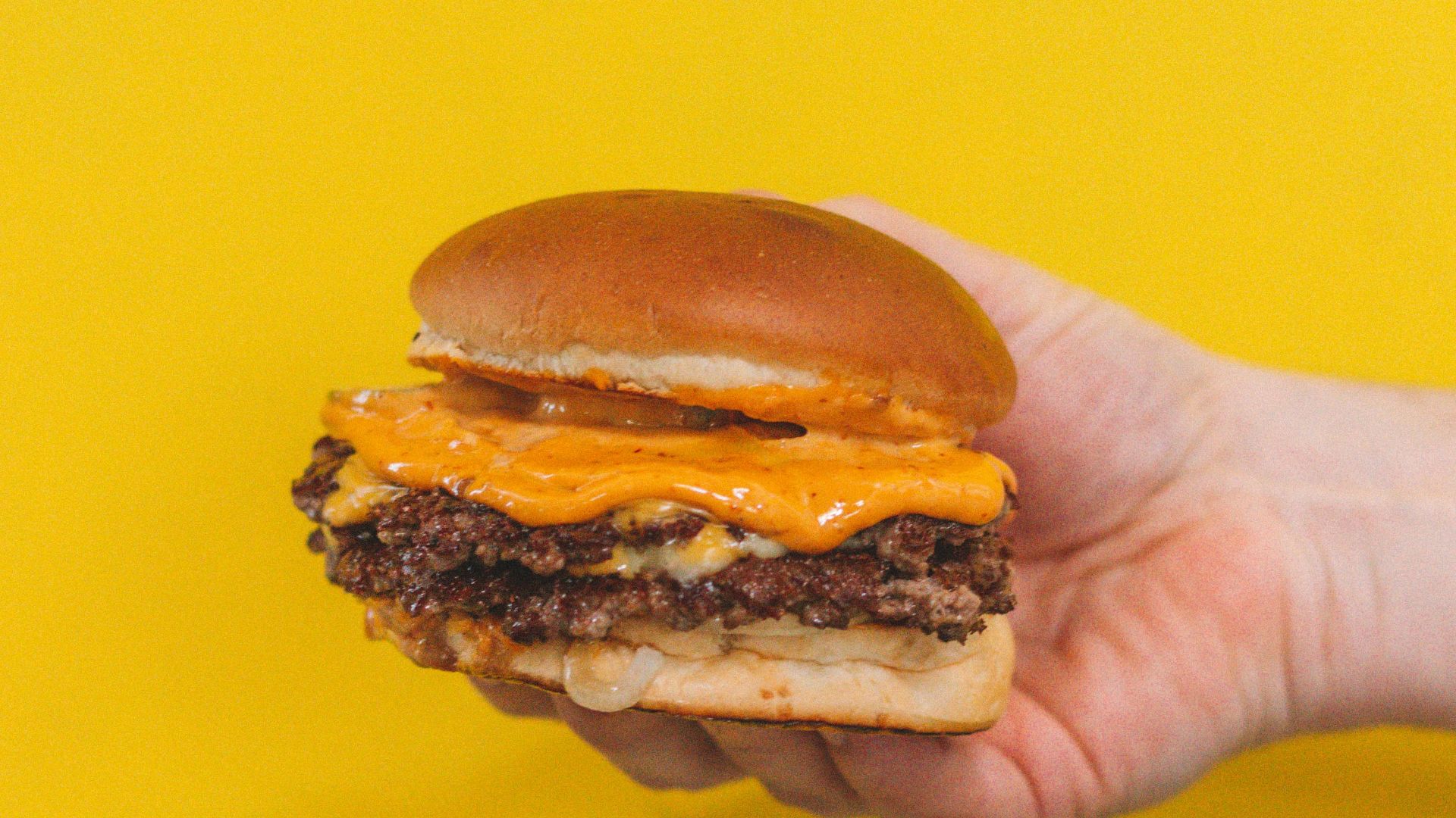 person holding burger with patty