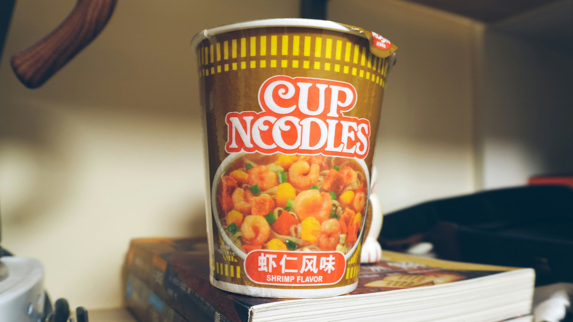 a cup of noodles sitting on top of a stack of books