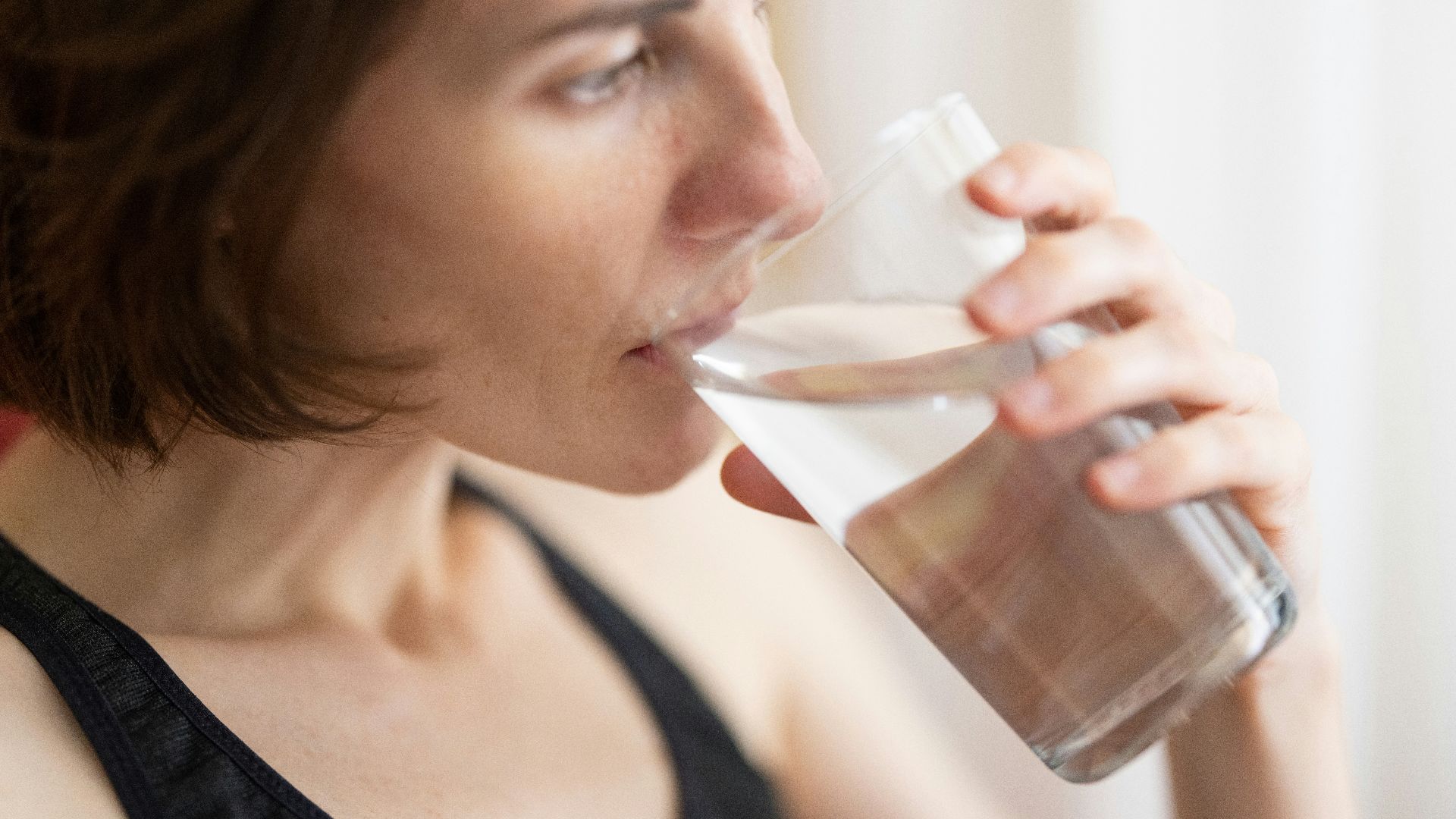 woman in black tank top drinking water