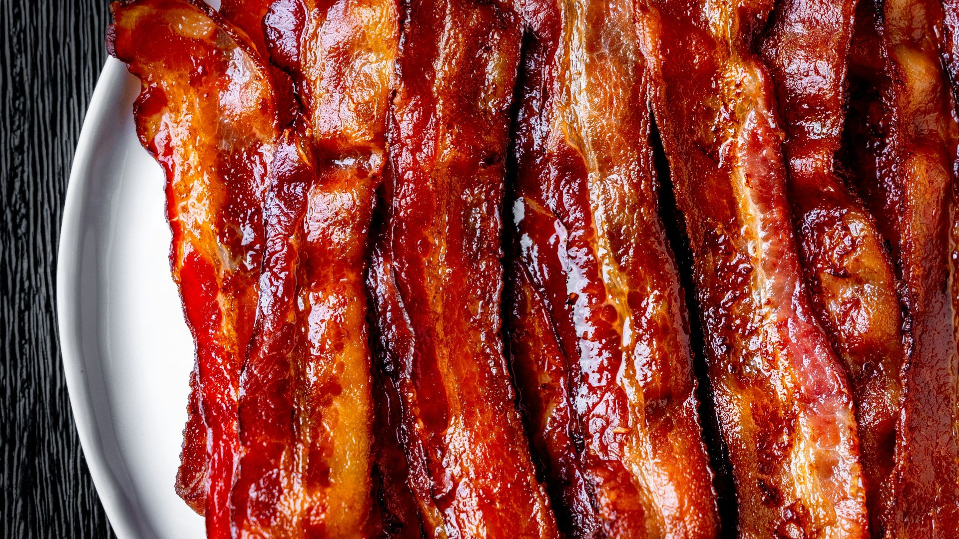 a white plate topped with bacon strips on top of a table