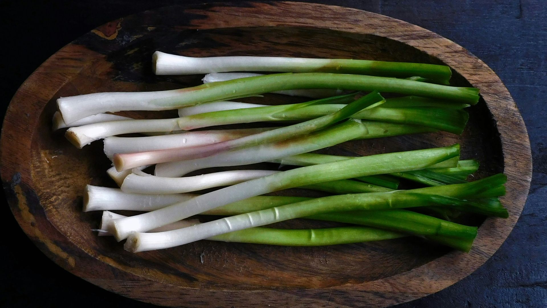 a wooden bowl filled with green and white onions