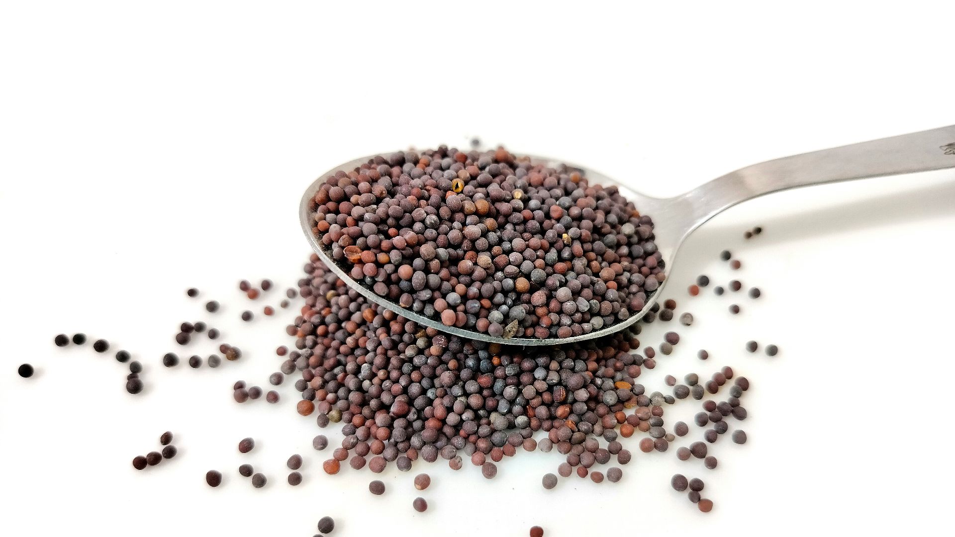 a spoon filled with black seed on top of a white table