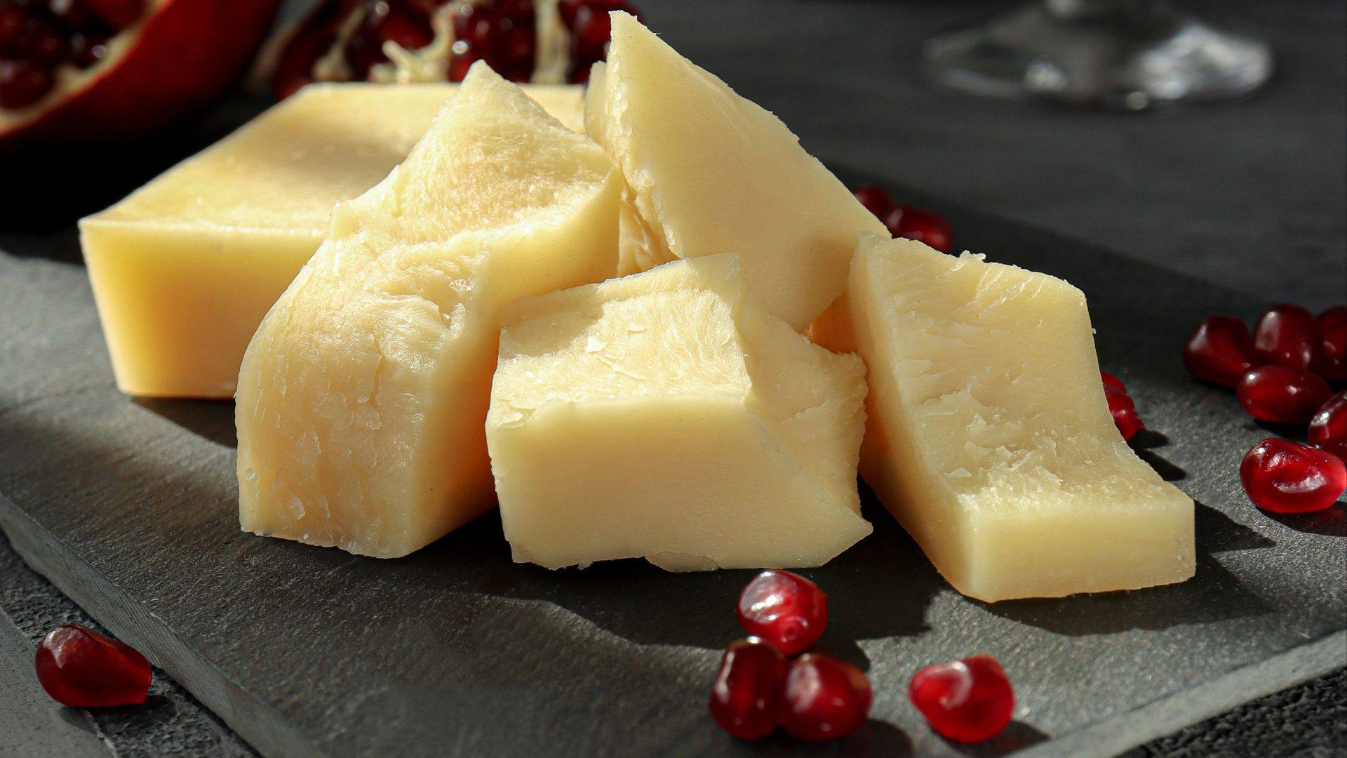 sliced cheese on black plate beside wine glass