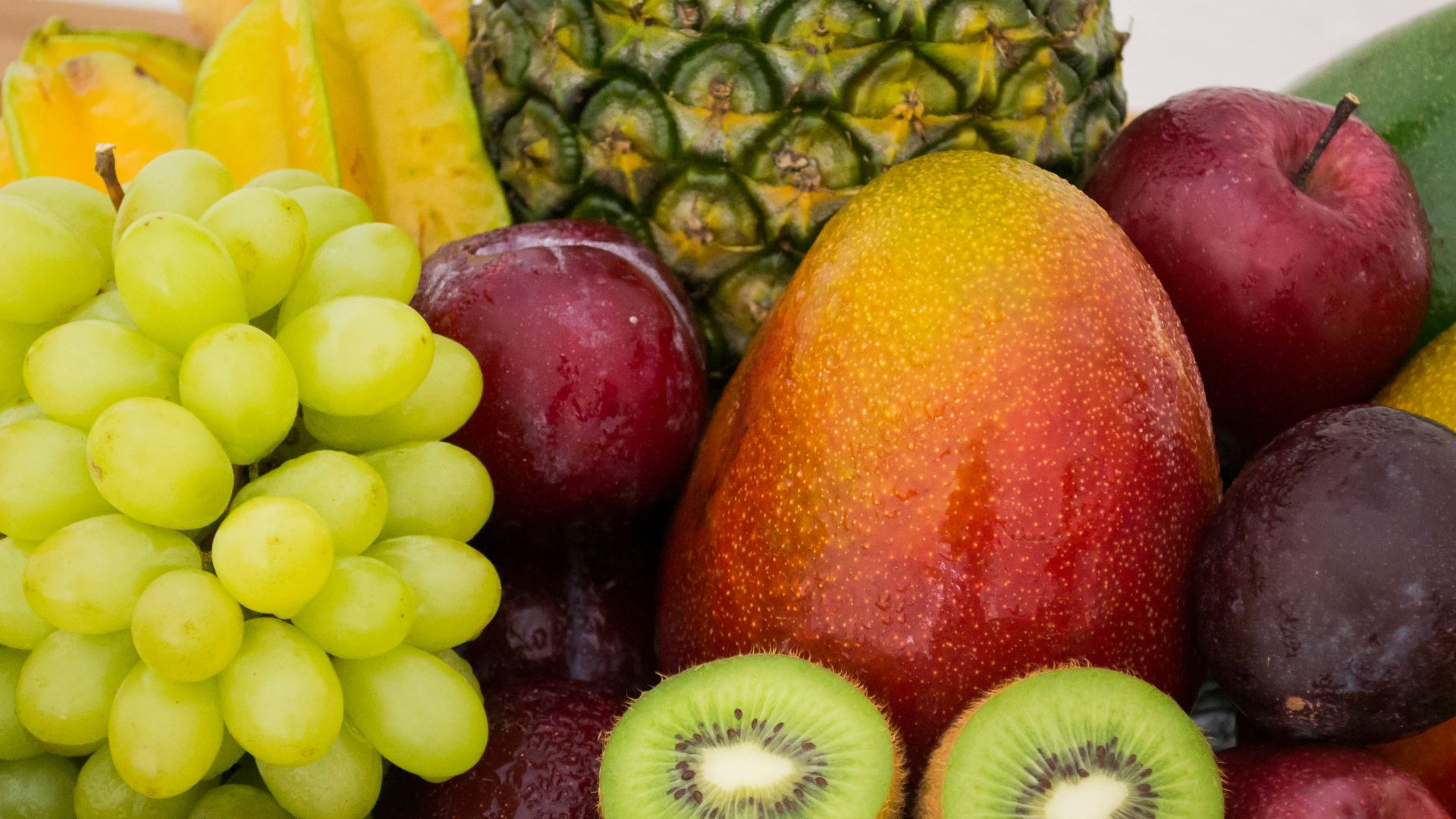 red apple fruit beside green apple and yellow fruit on brown woven basket