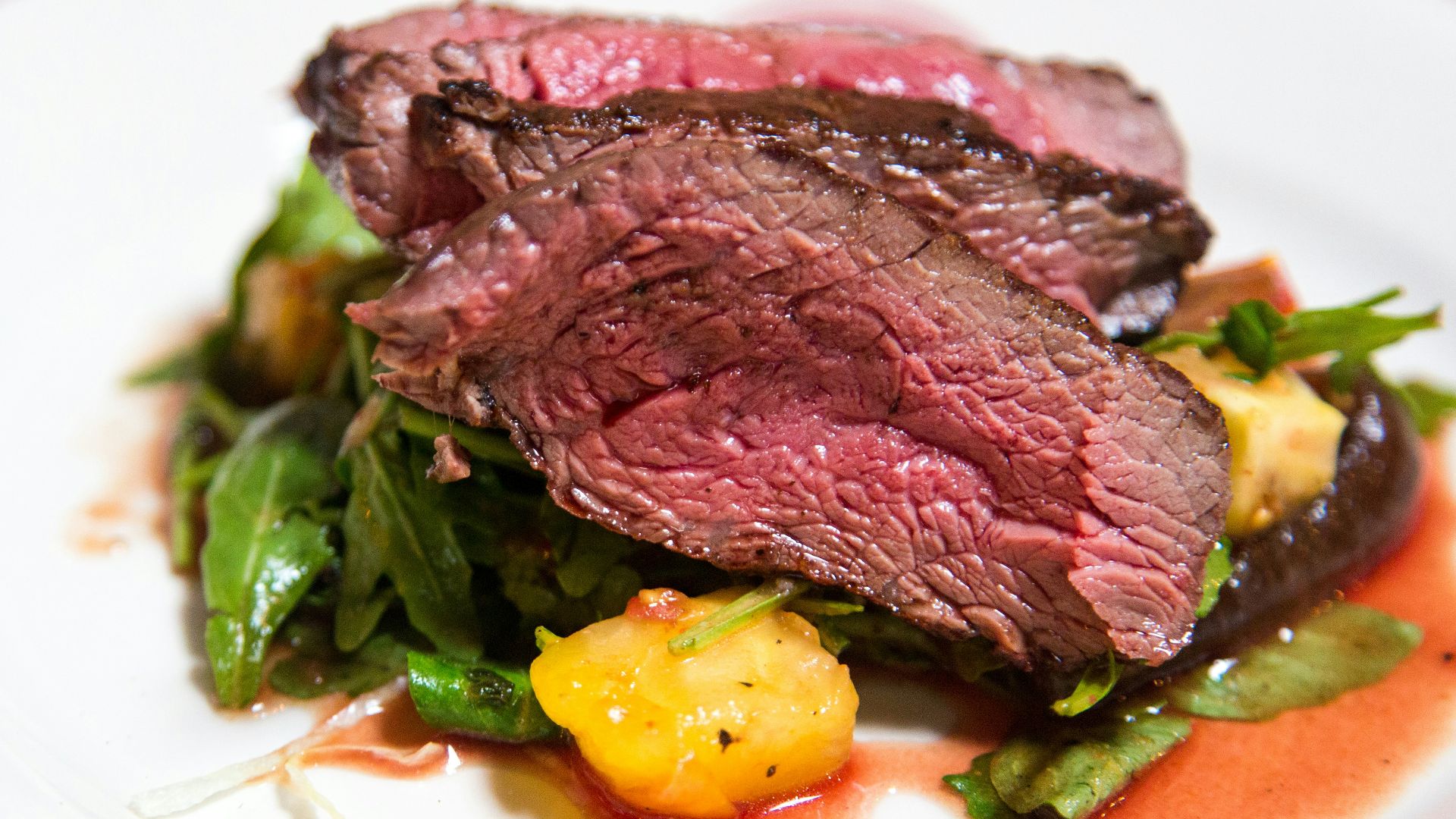 medium rare sliced steak in white ceramic plate