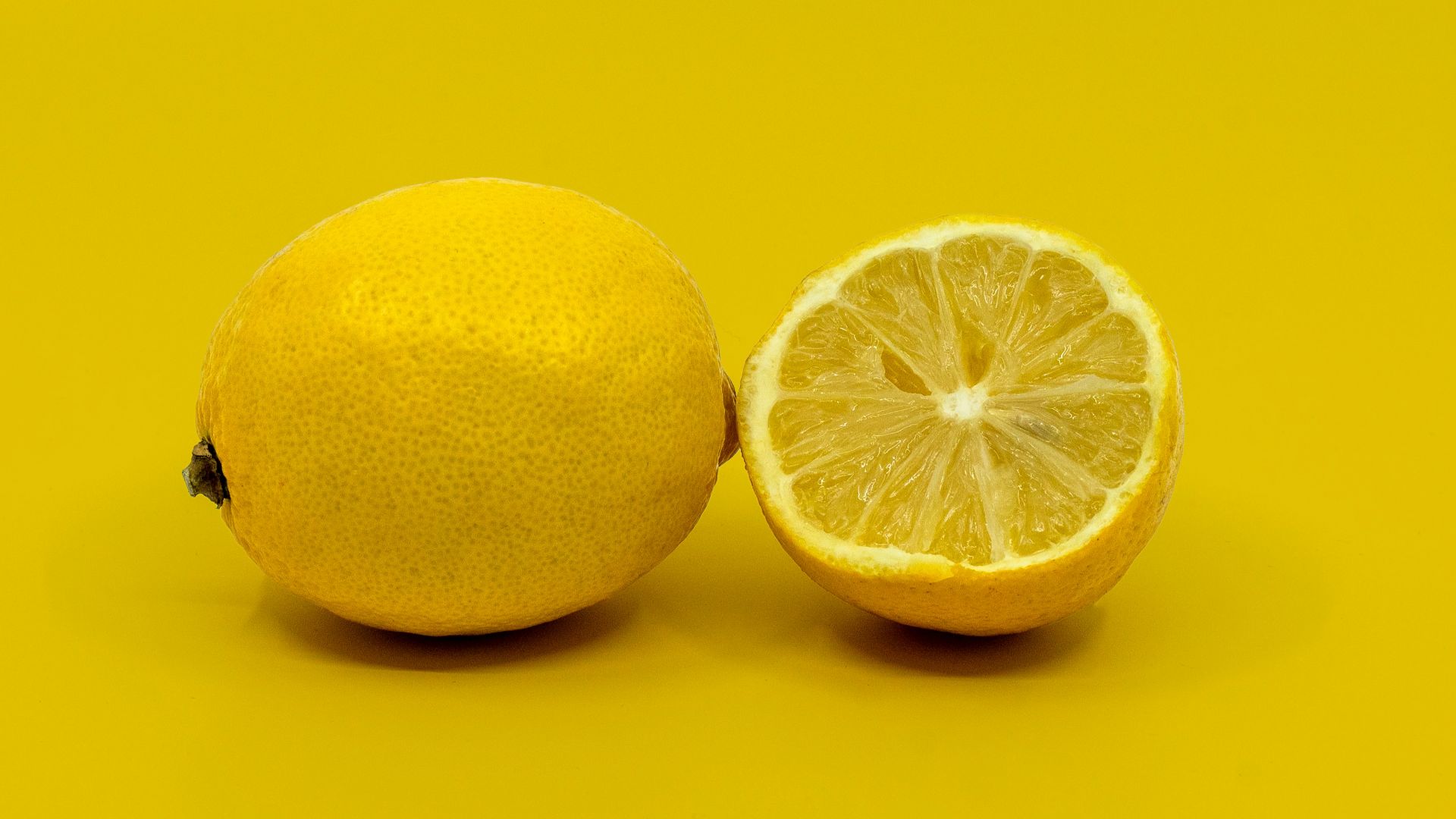 a half and a whole lemon on a yellow background
