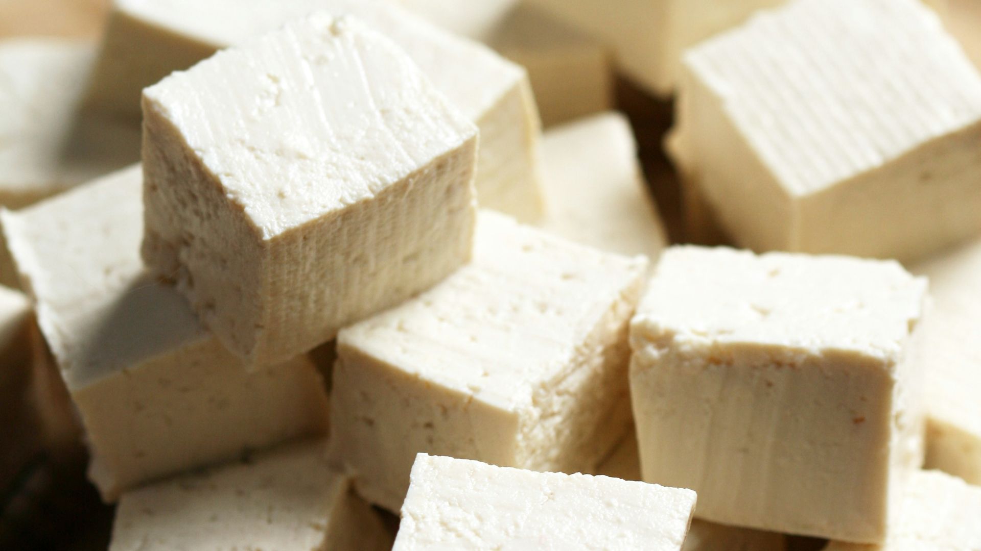 A pile of tofu cubes sitting on top of a cutting board