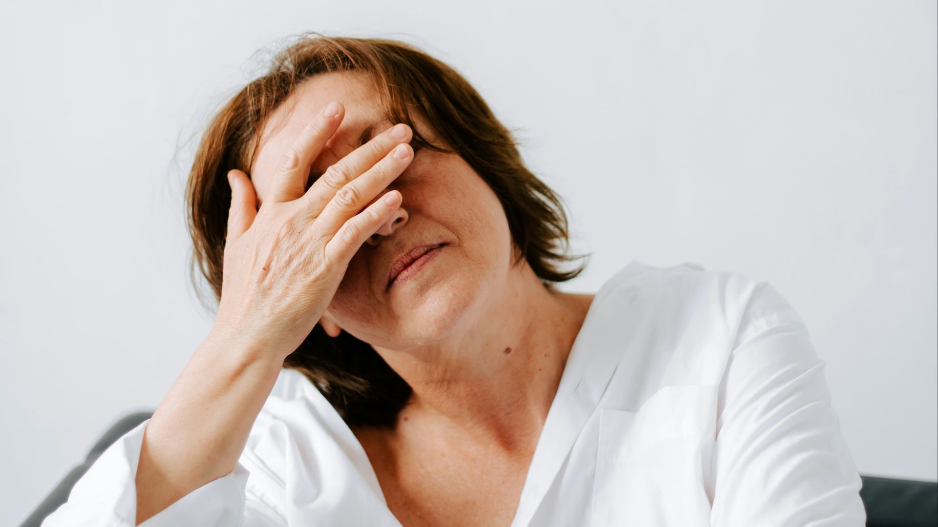 a woman sitting on a couch holding her hands to her face
