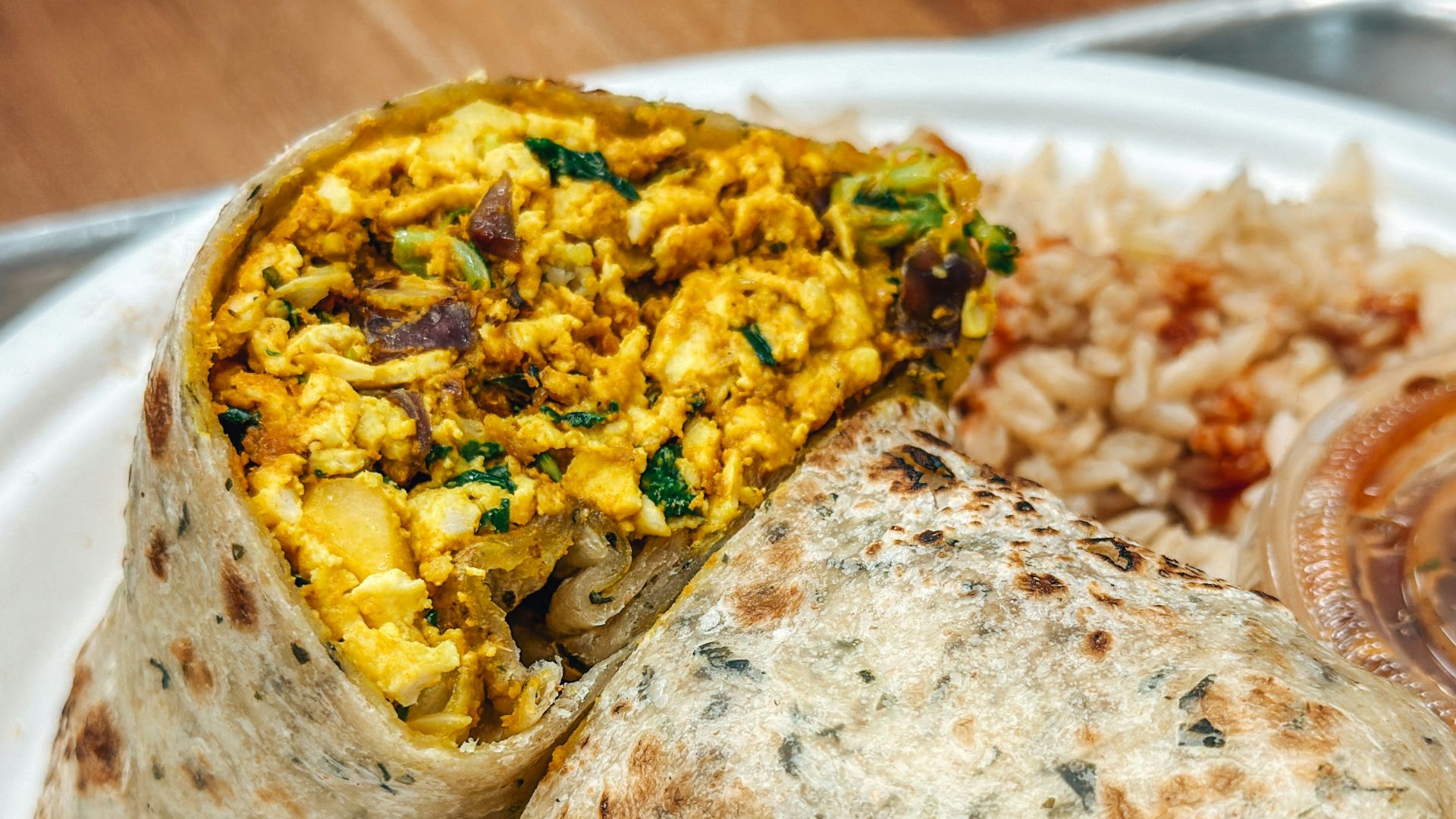 a white plate topped with a burrito and rice