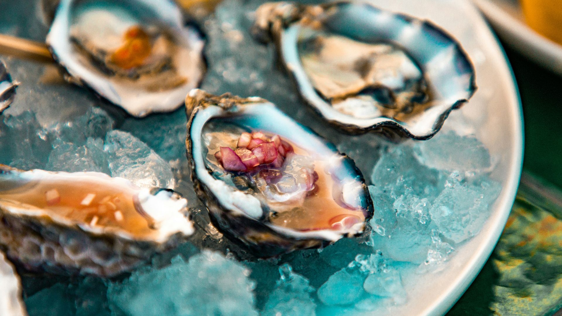 a plate of oysters on ice with lemon wedges