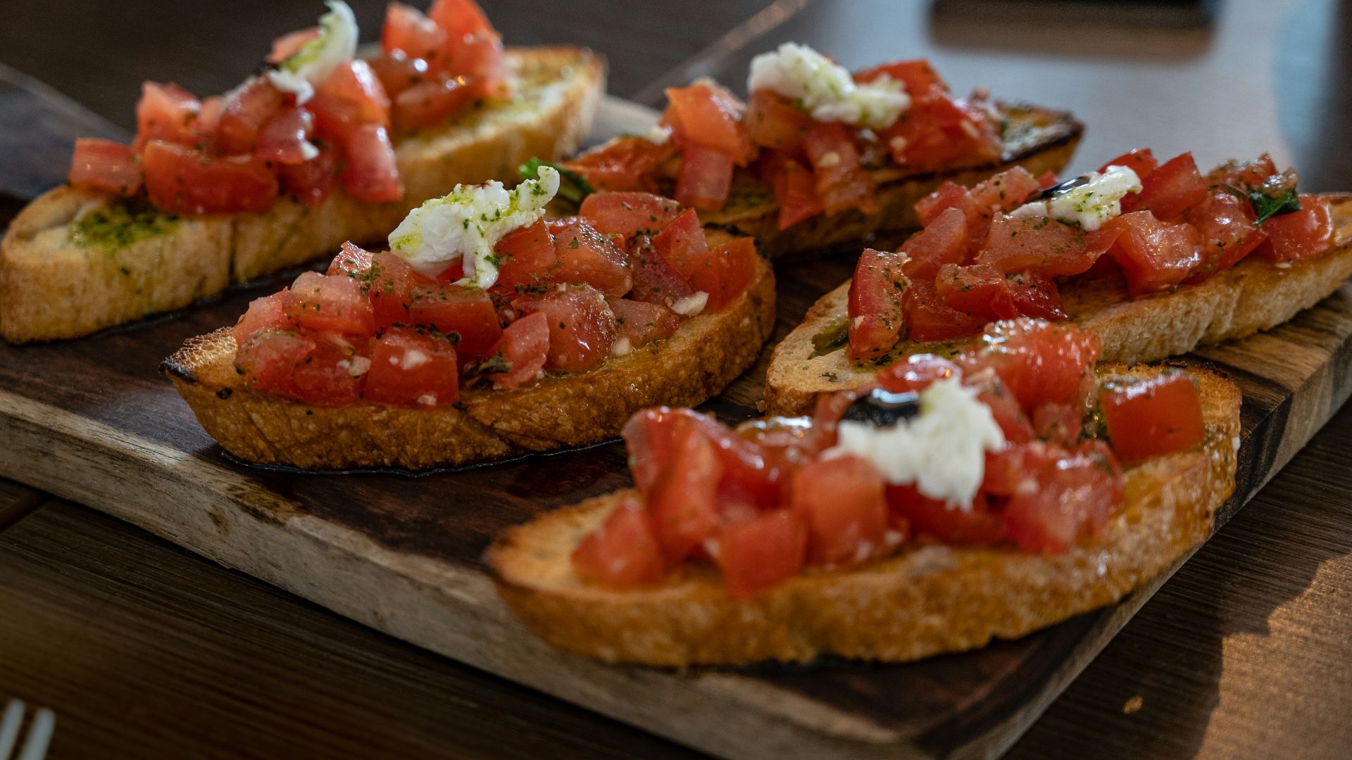 brown bread with tomato and green vegetable on brown wooden table