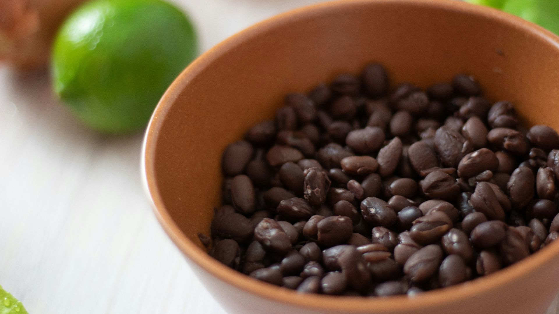 a bowl filled with black beans next to limes