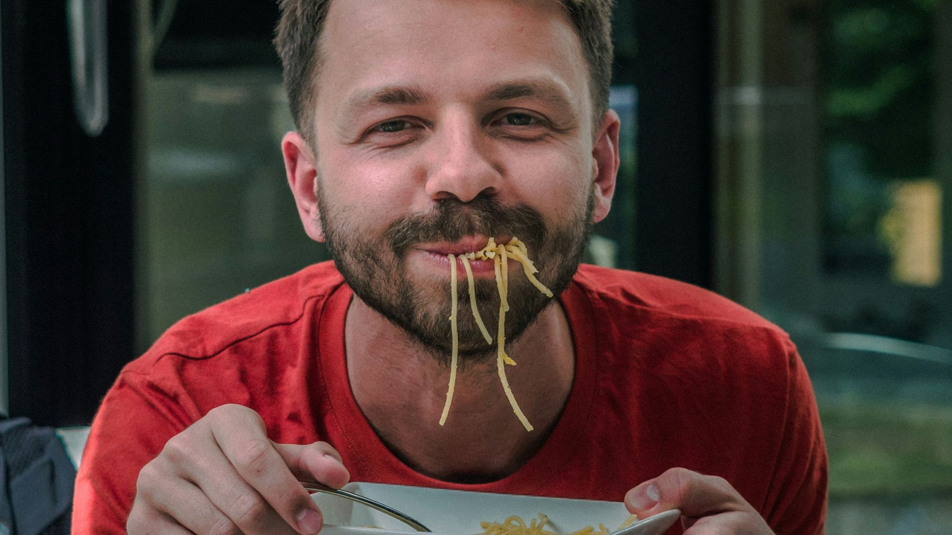 man in red crew neck t-shirt holding white and red labeled can