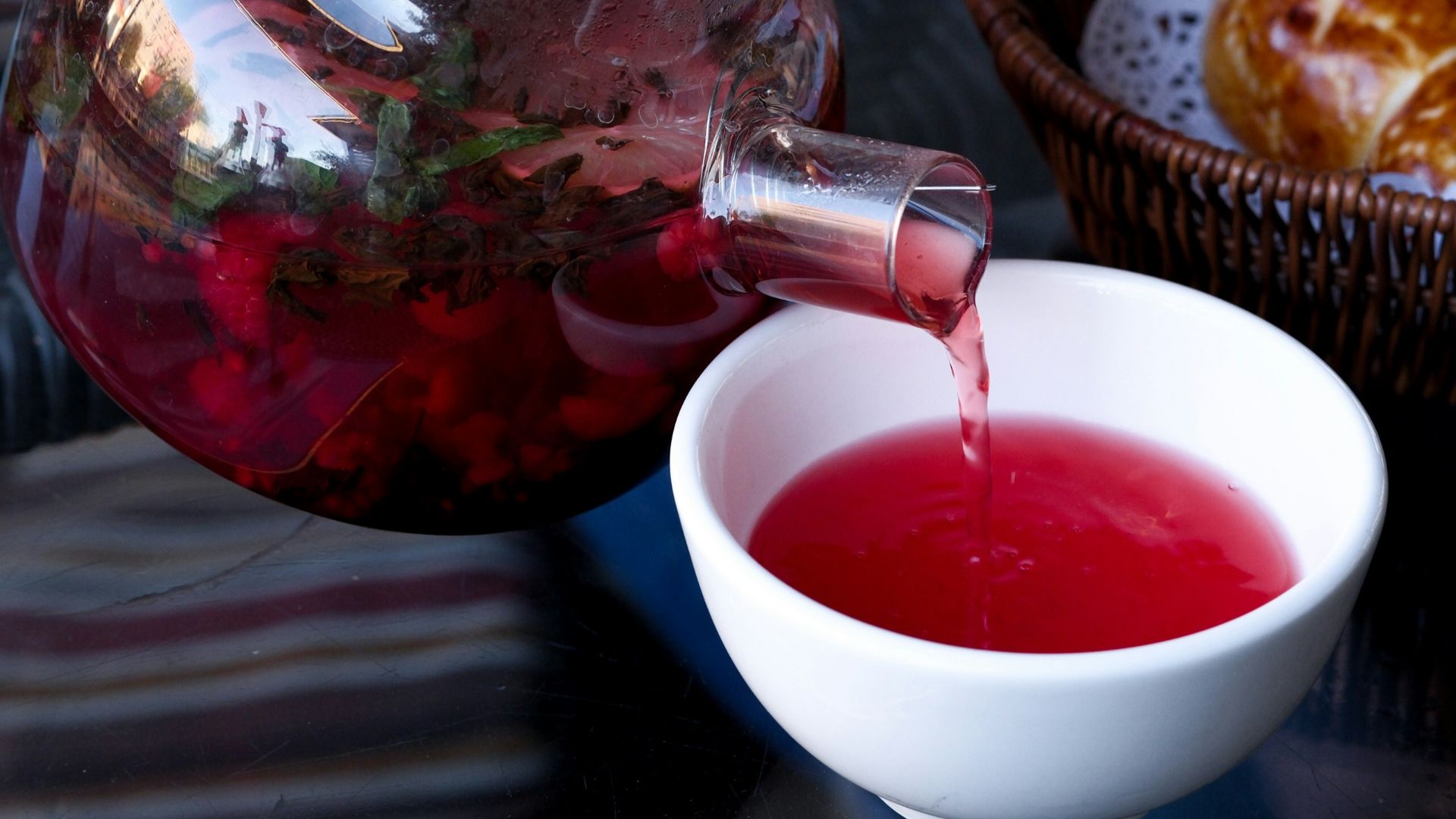 A person pours tea into a glass pitcher