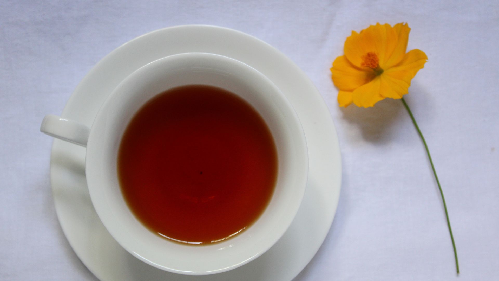 a cup of tea next to a yellow flower