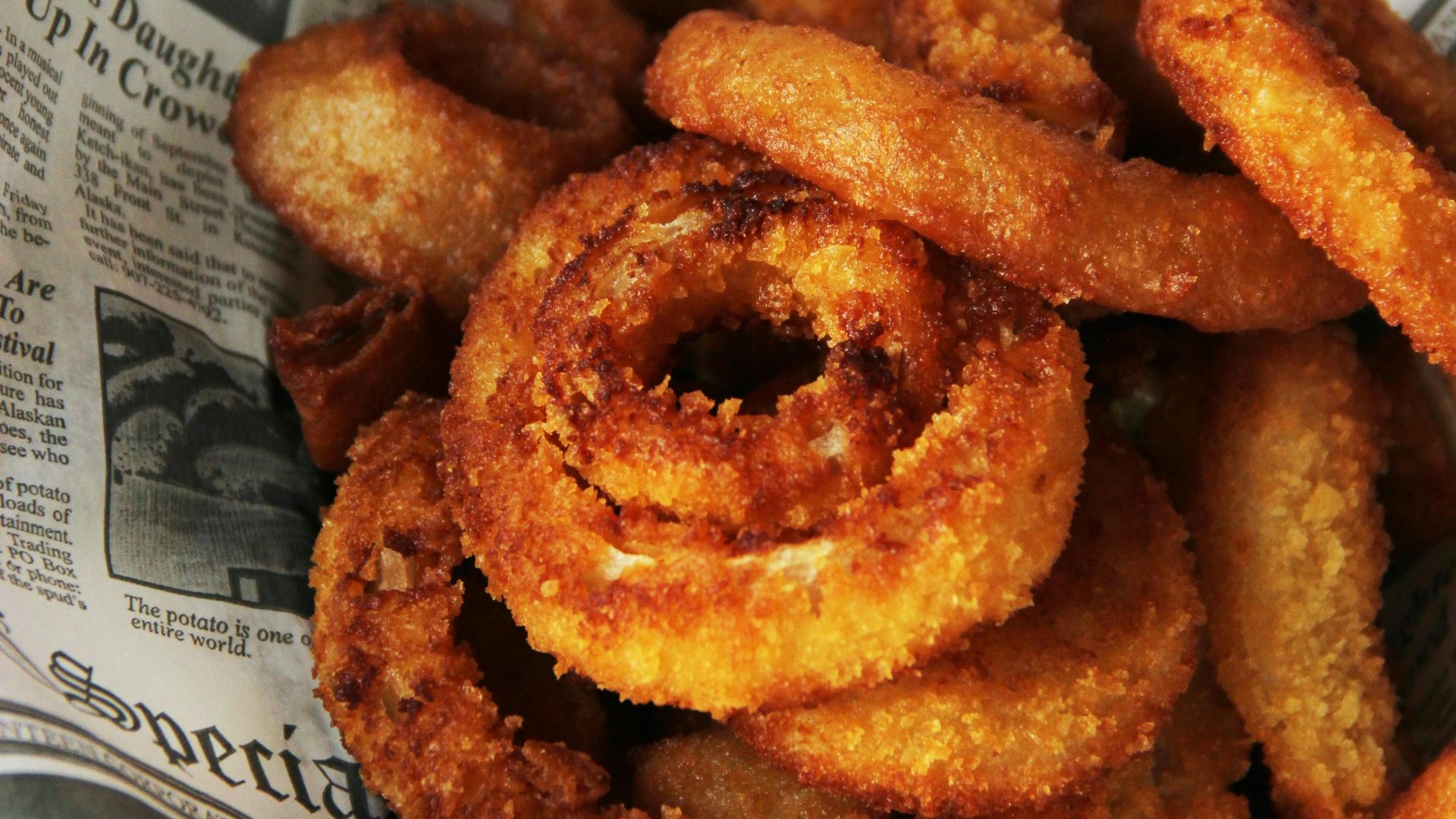 a pile of fried onion rings sitting on top of a newspaper