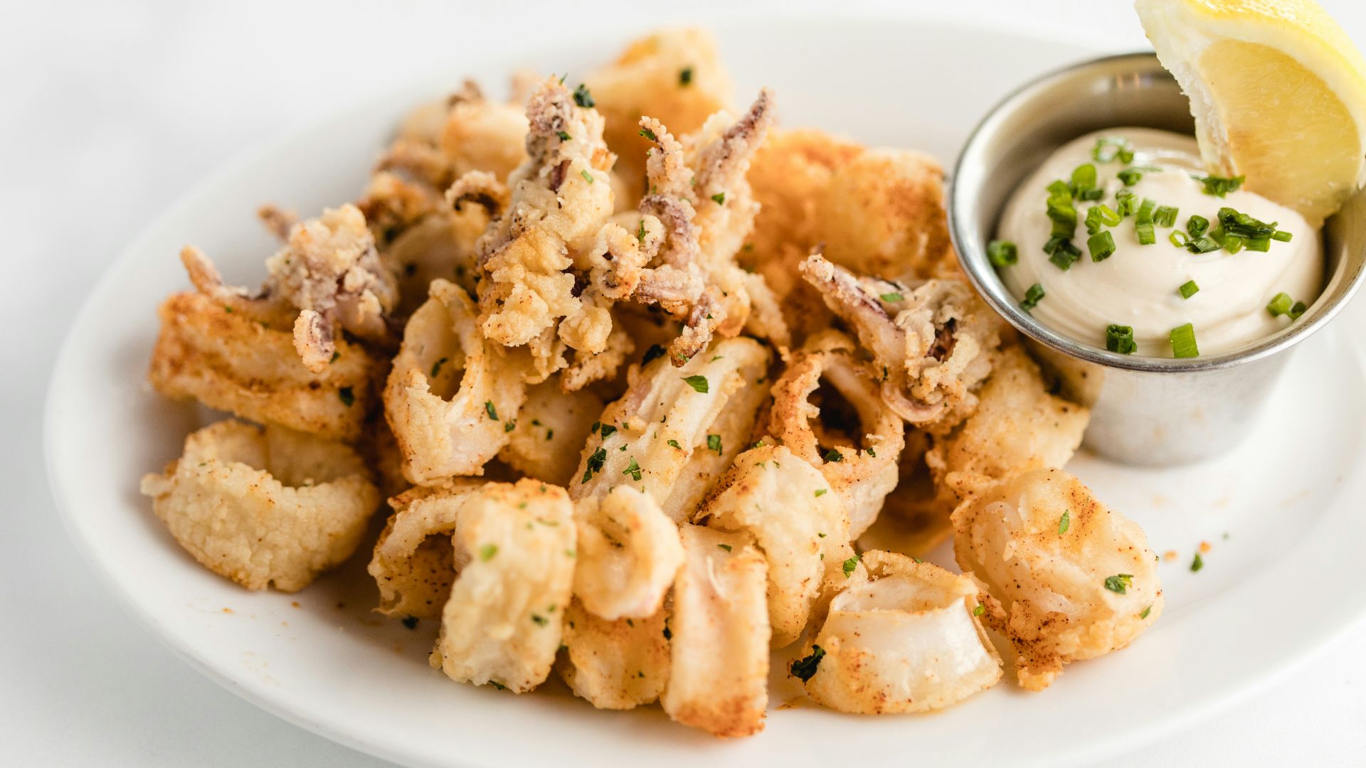 a white plate topped with fried food and a dipping sauce