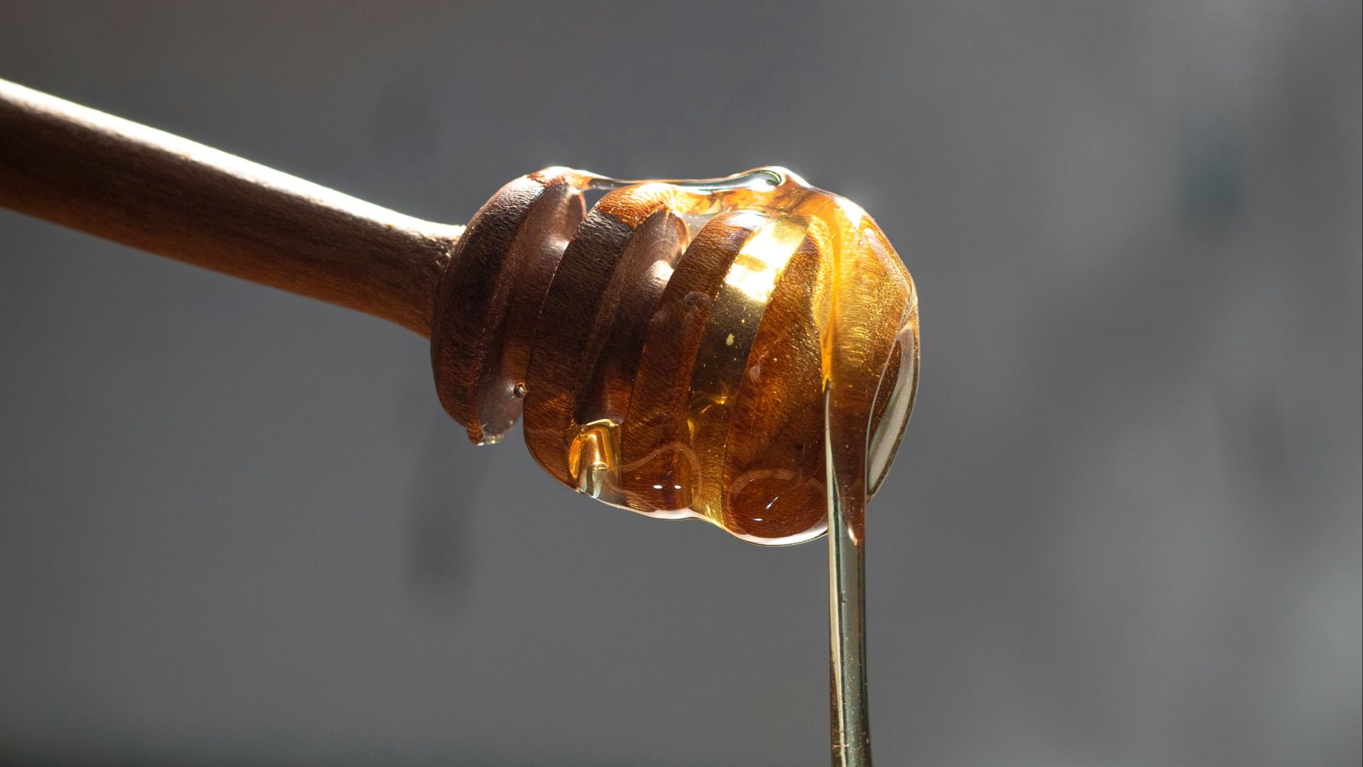 a honey dip being poured into a wooden bowl