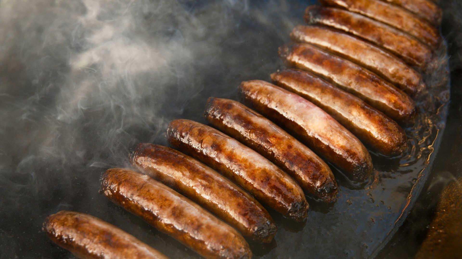 a bunch of sausages are cooking on a grill