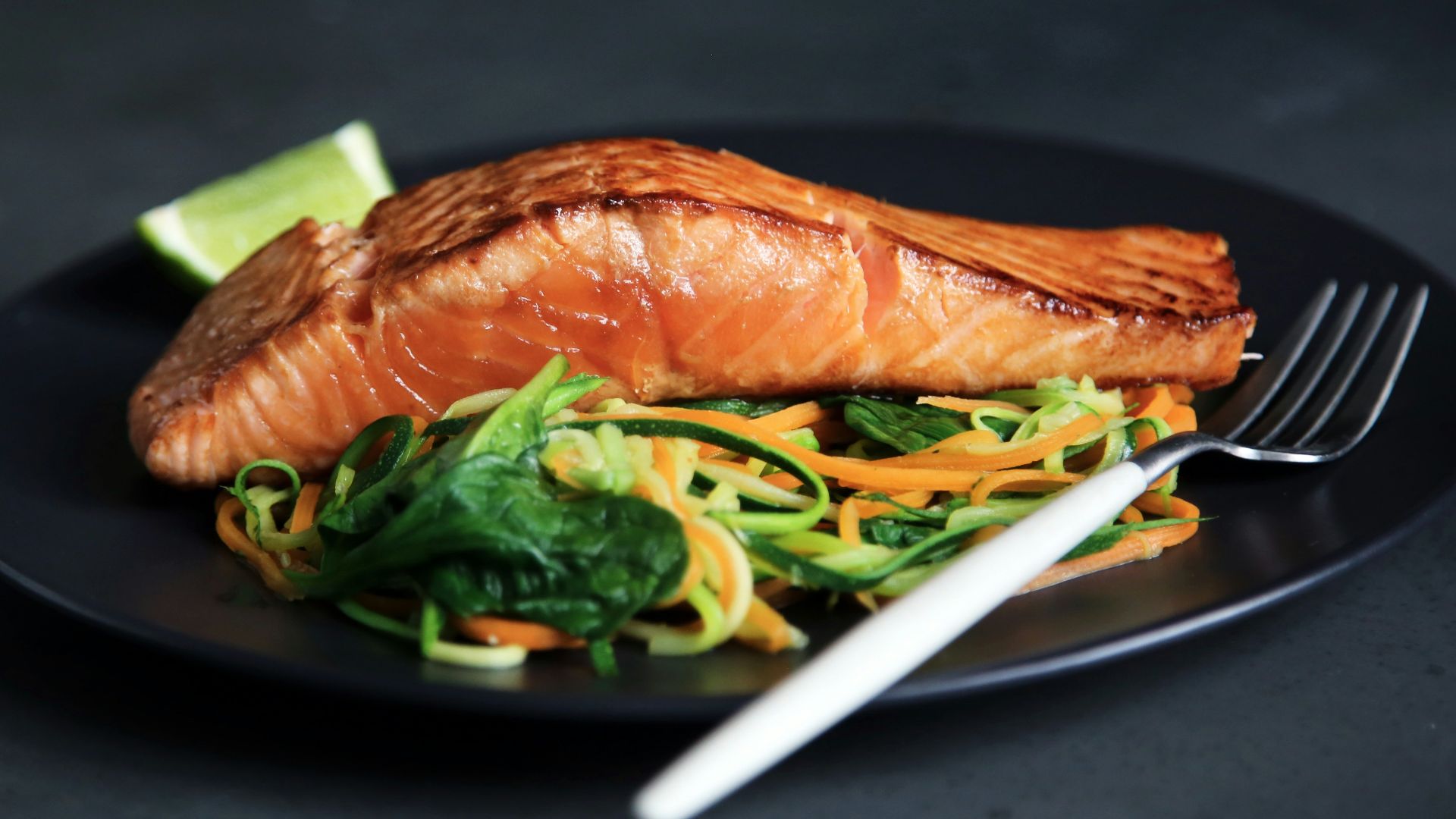 grilled fish, cooked vegetables, and fork on plate