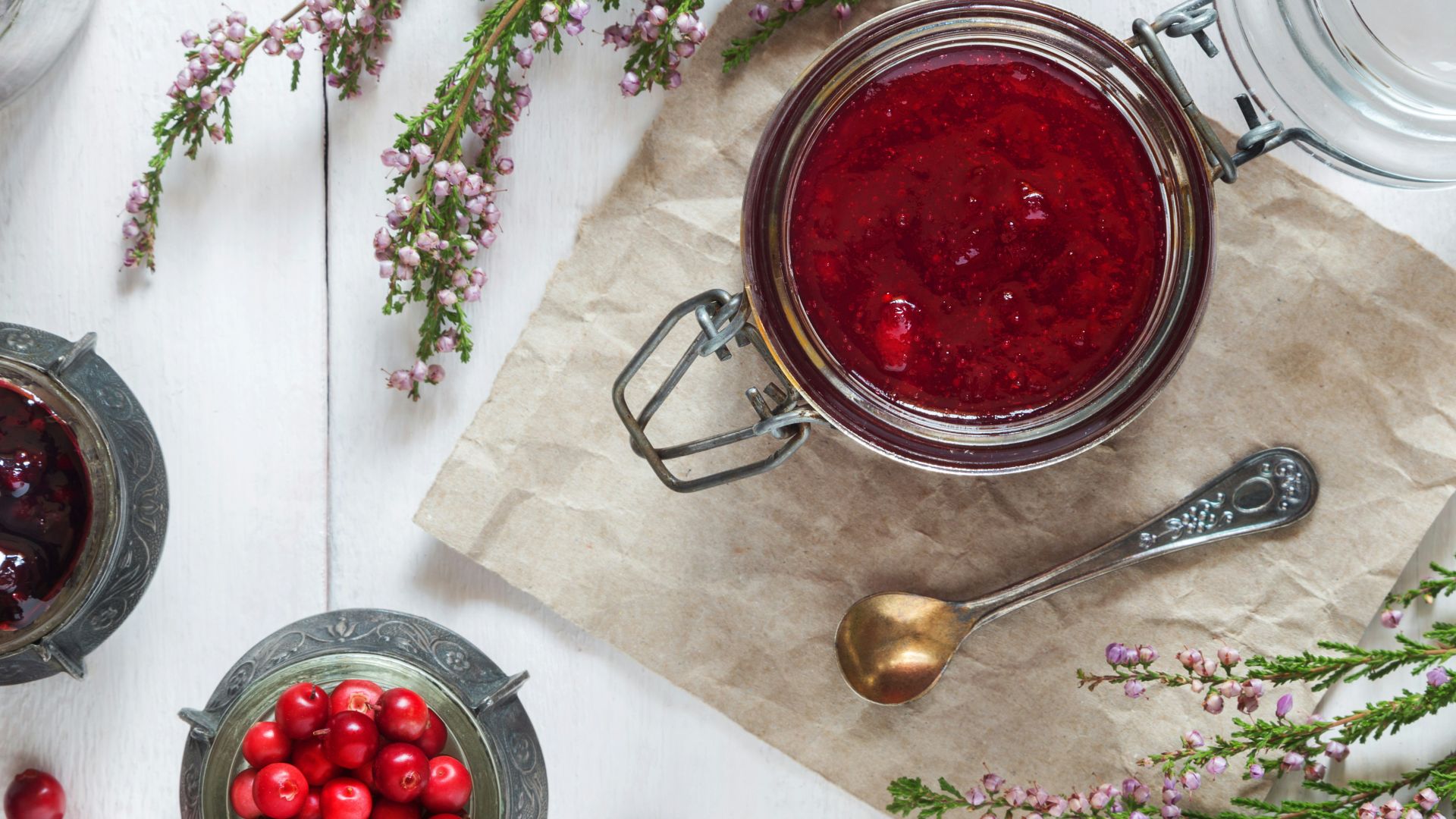 a table with a bowl of red berries and a spoon