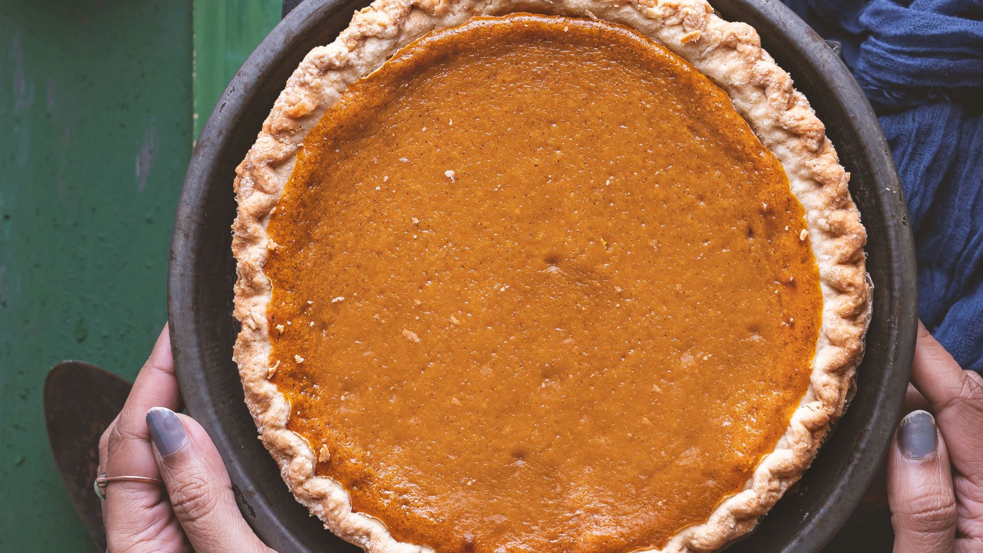 a person holding a pie on top of a green table