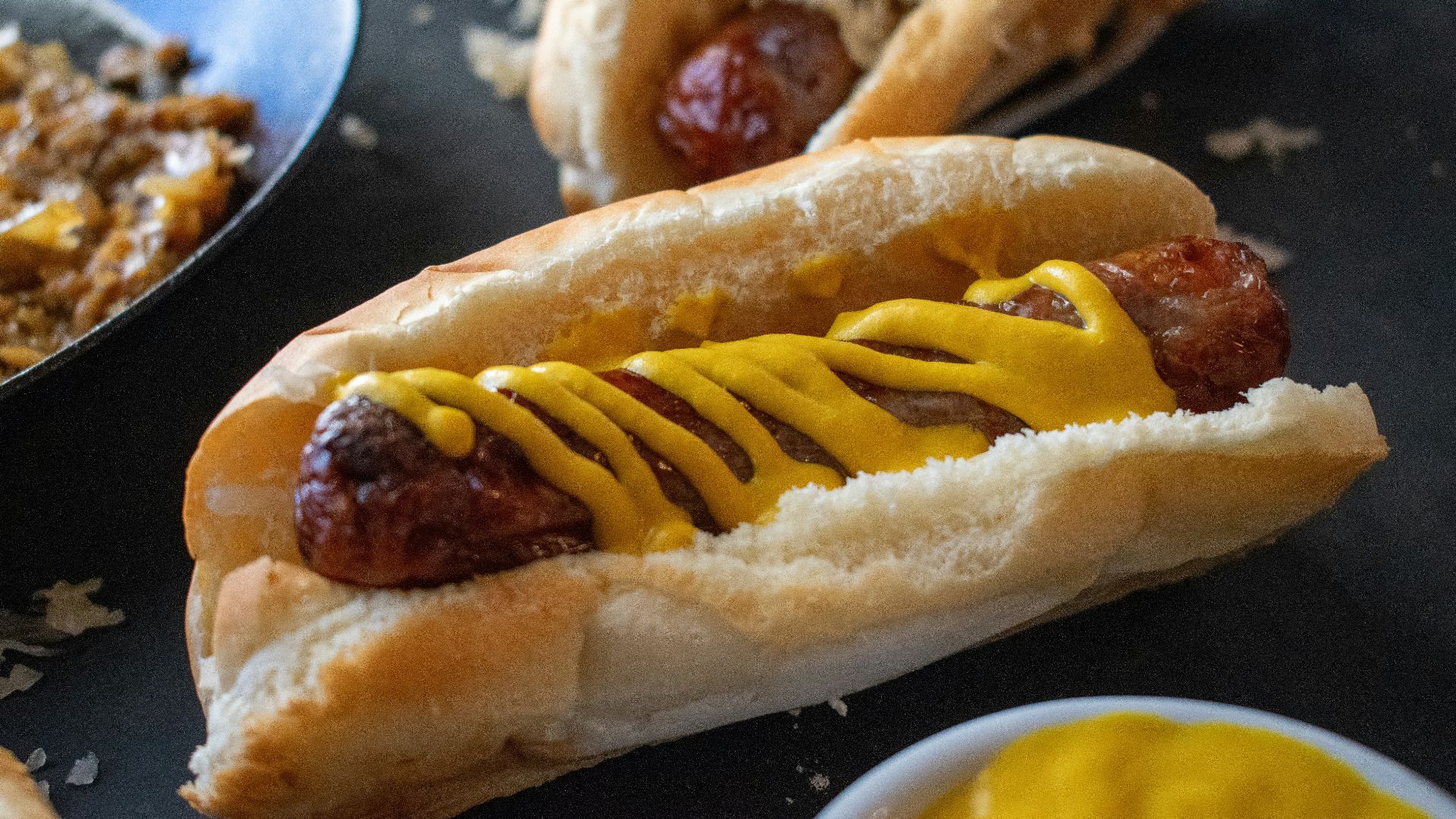 a hot dog with mustard on a bun