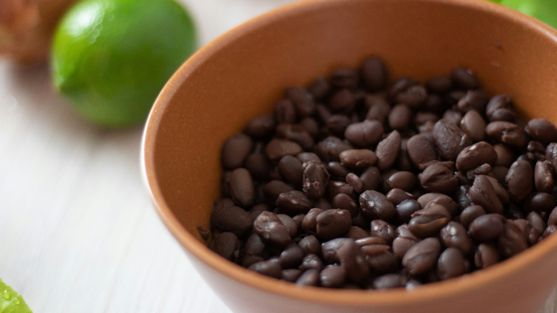 a bowl filled with black beans next to limes