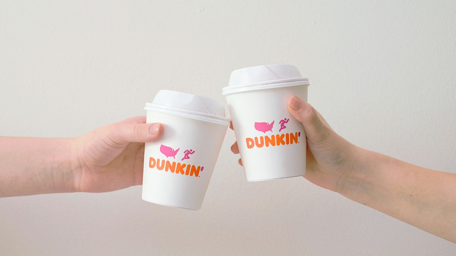 two people with white Dunkin' Donuts paper cups