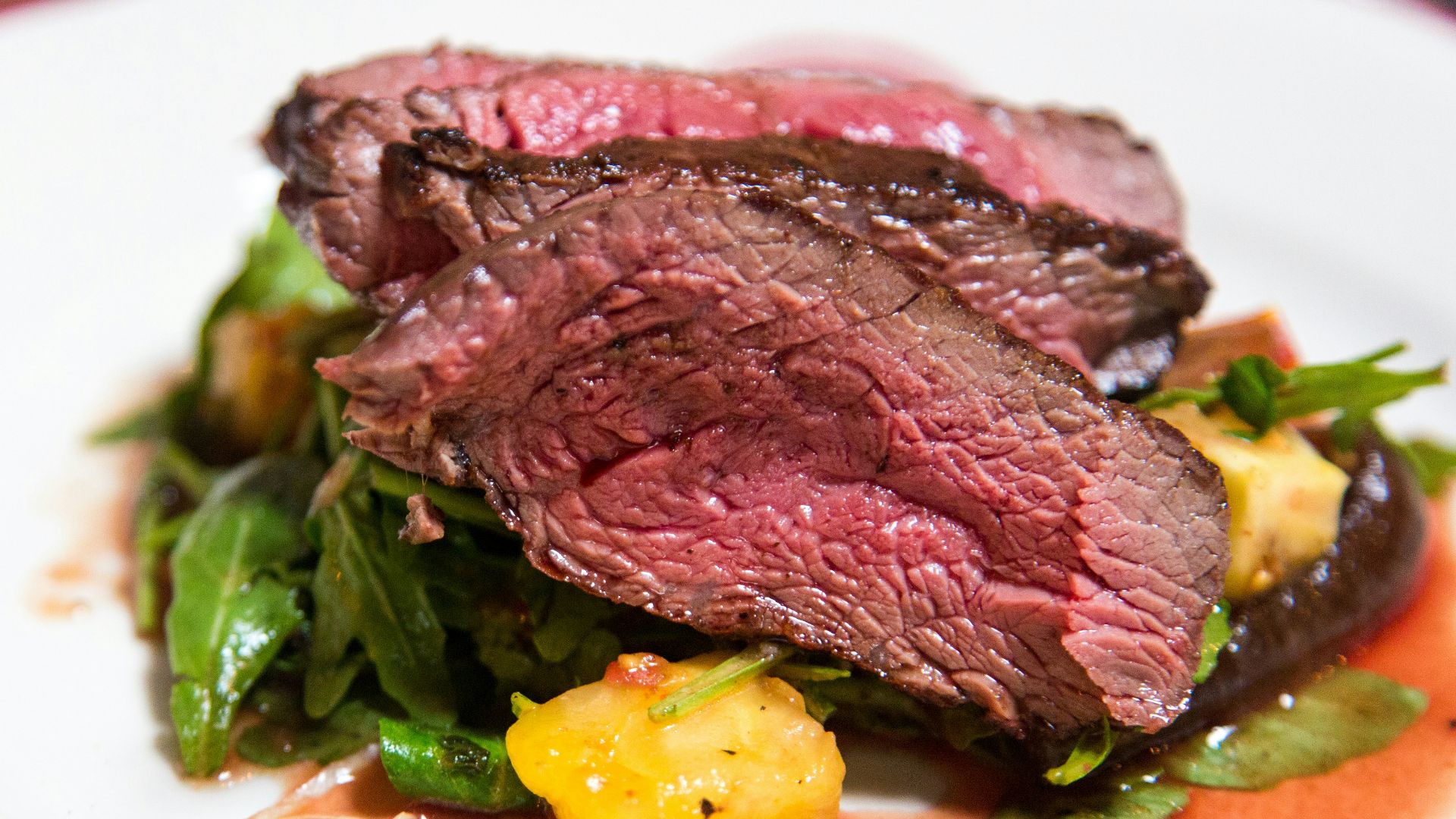 medium rare sliced steak in white ceramic plate
