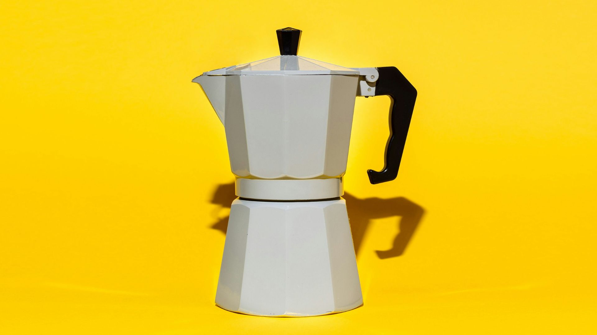 a stove top coffee maker on a yellow background