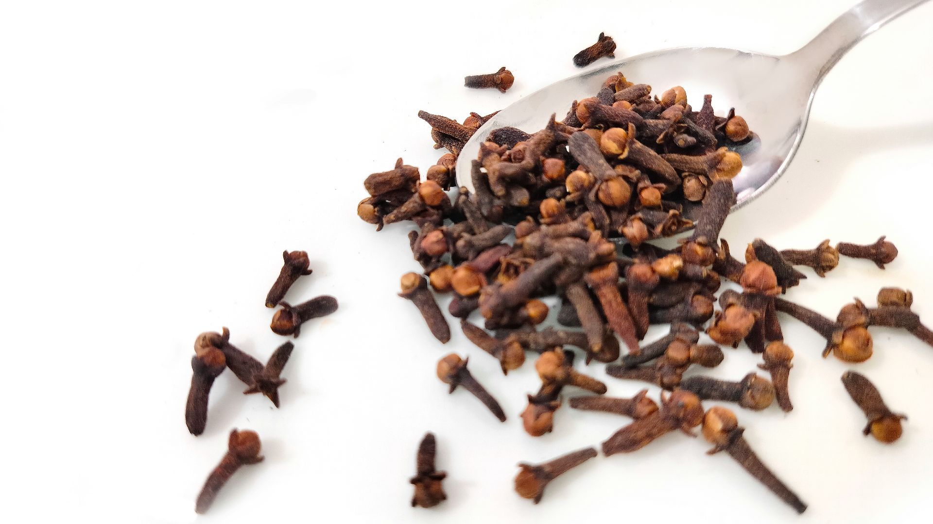 a spoon full of cloves on a white surface