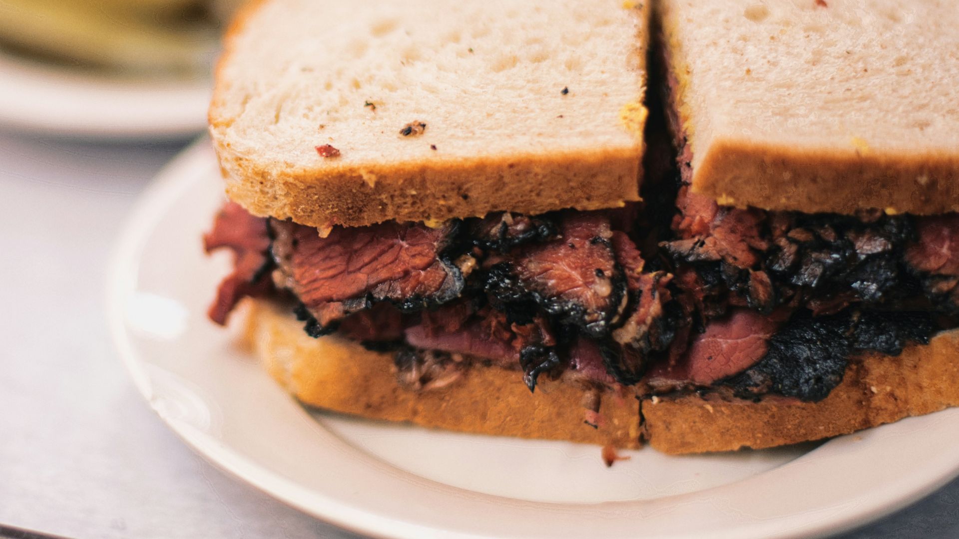 a roast beef sandwich on a plate with pickles