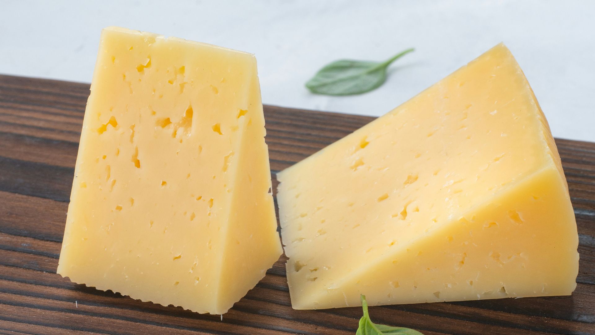 a couple of pieces of cheese sitting on top of a wooden cutting board
