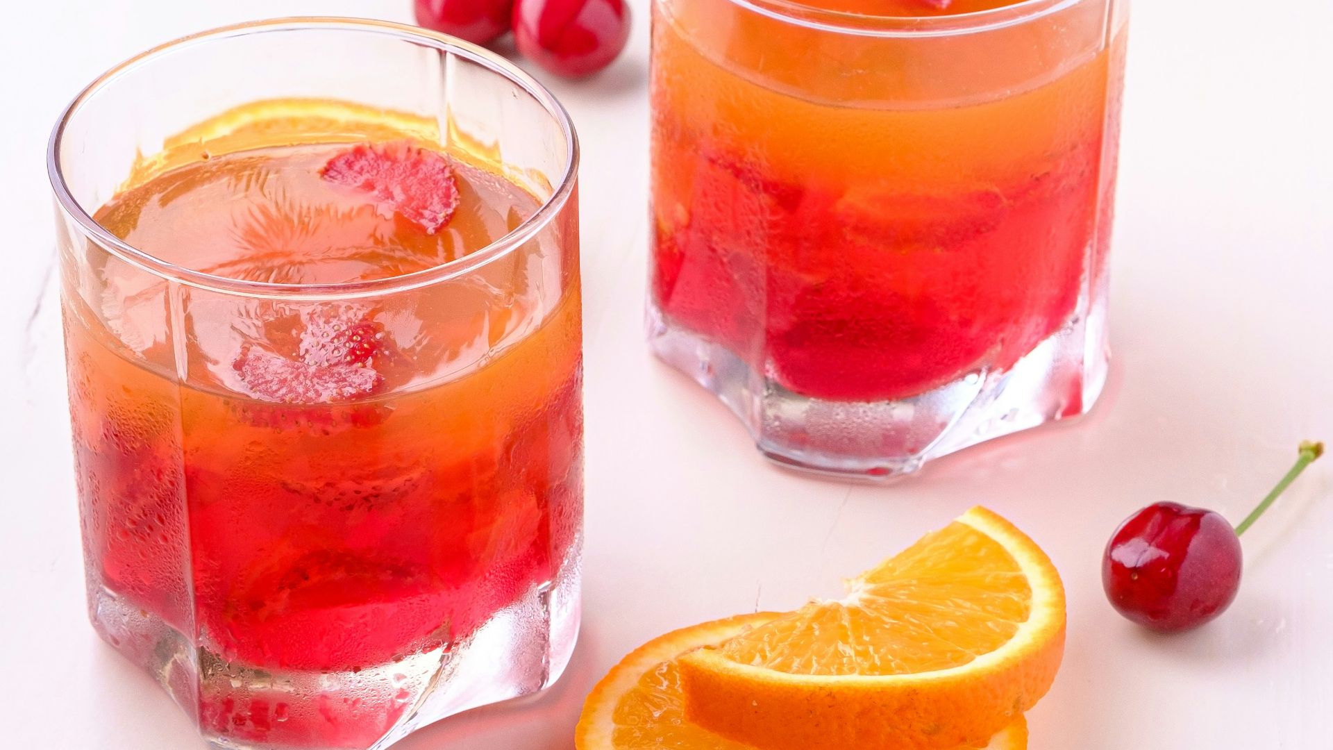 two orange and cherry drink in glasses