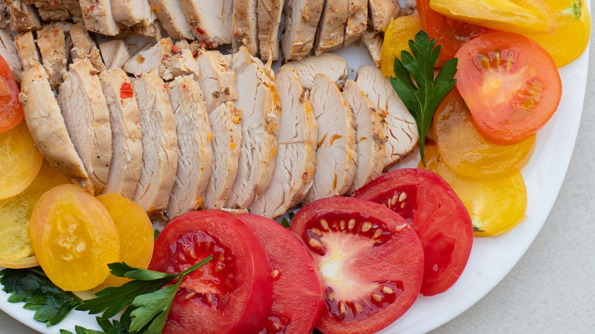 a white plate topped with sliced chicken and tomatoes