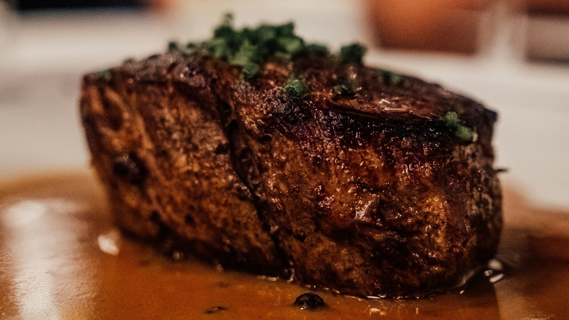 a piece of steak on a plate with sauce and garnish