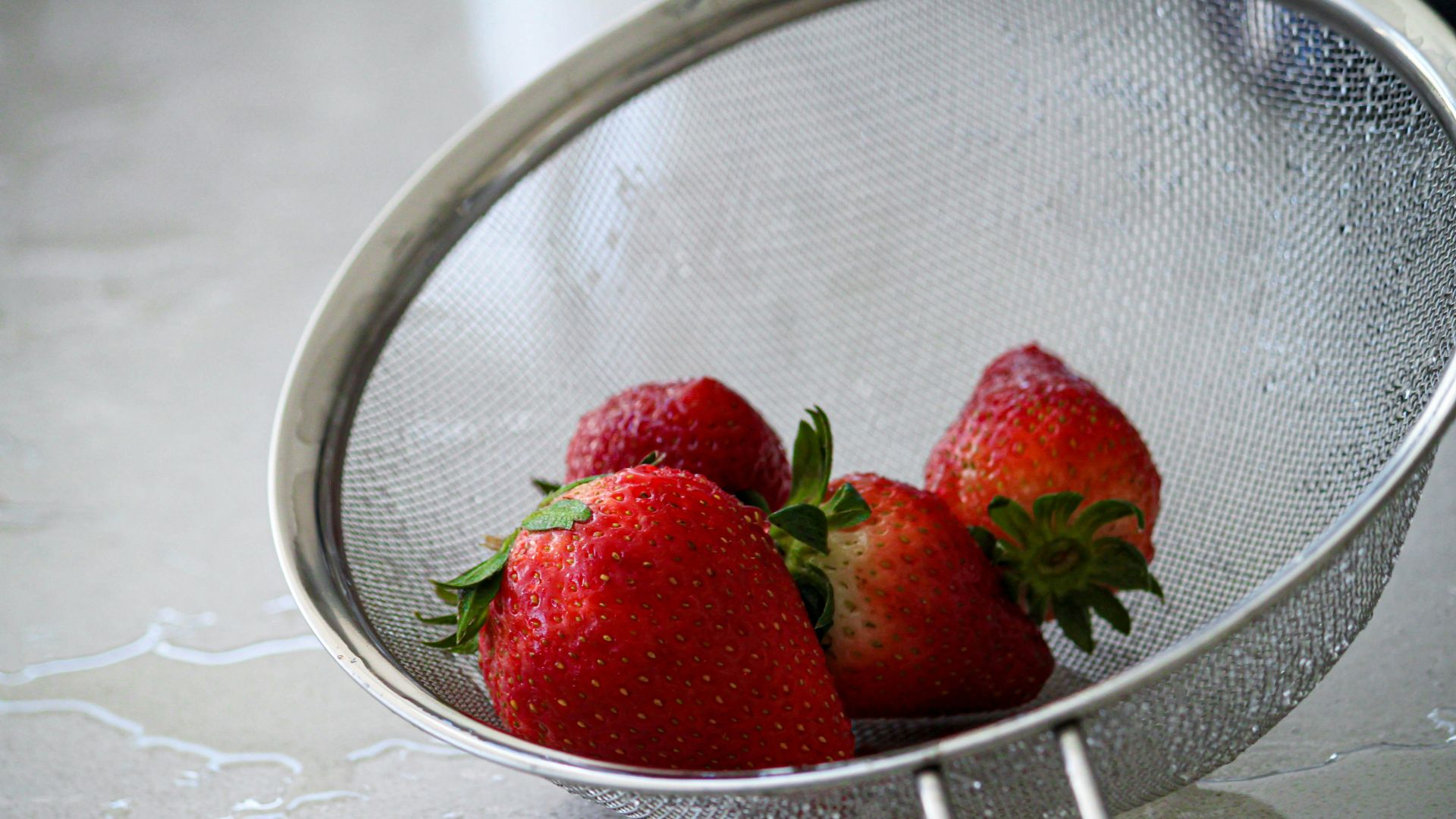 red strawberries in stainless steel strainer