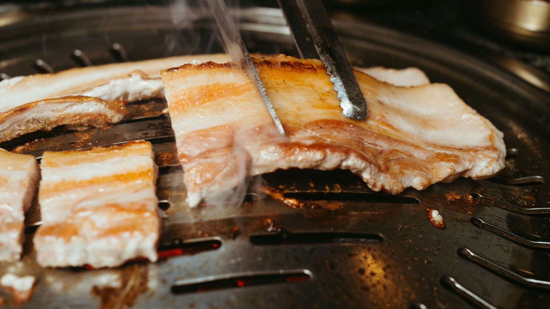 a person cutting meat on top of a grill