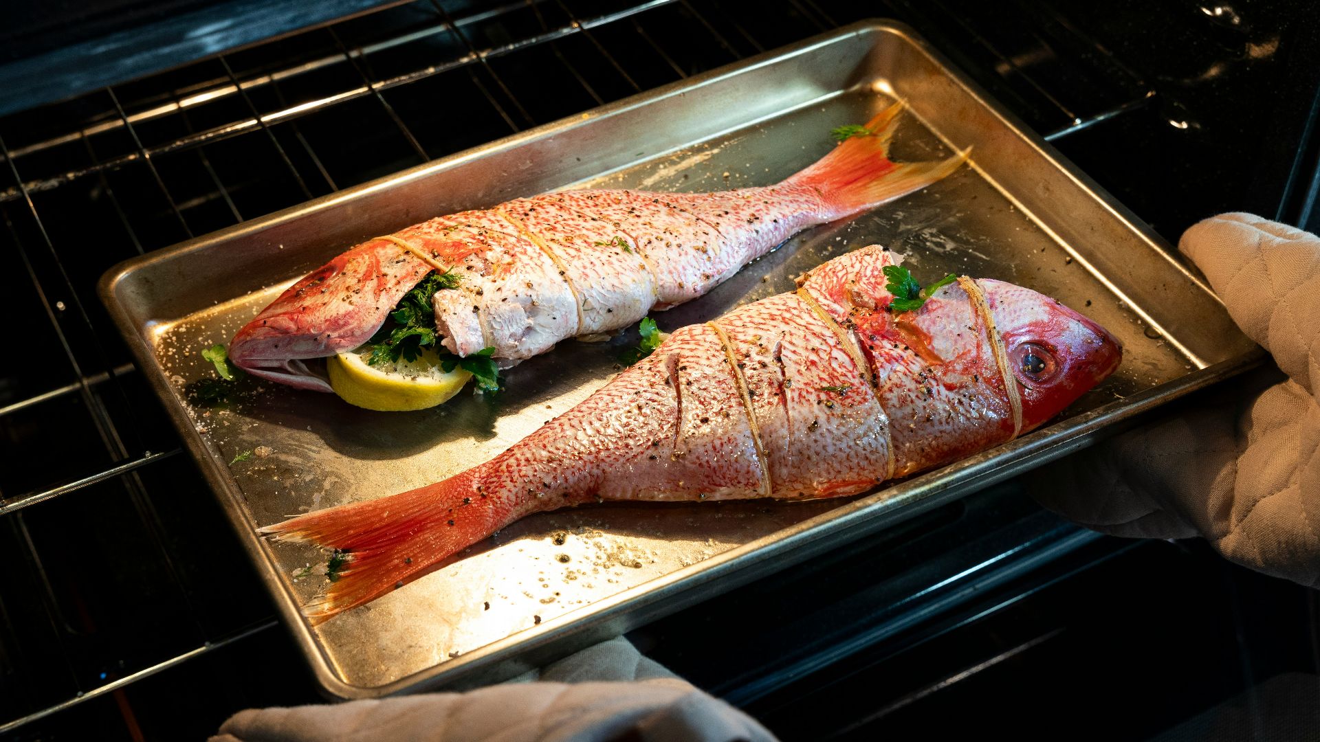 a person pulling a fish out of an oven